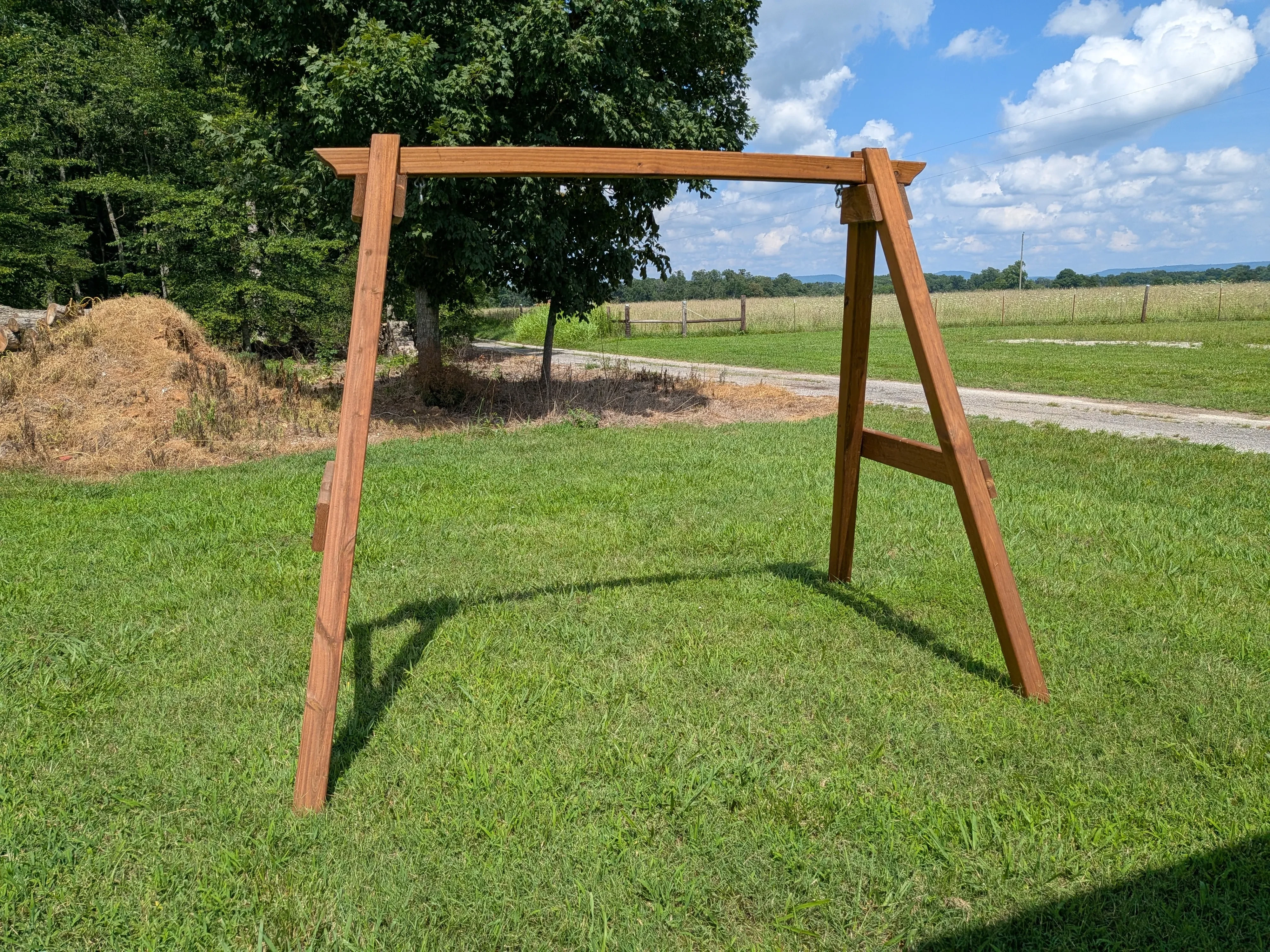 a front view of a wood stained and sealed a-frame structure in the grass