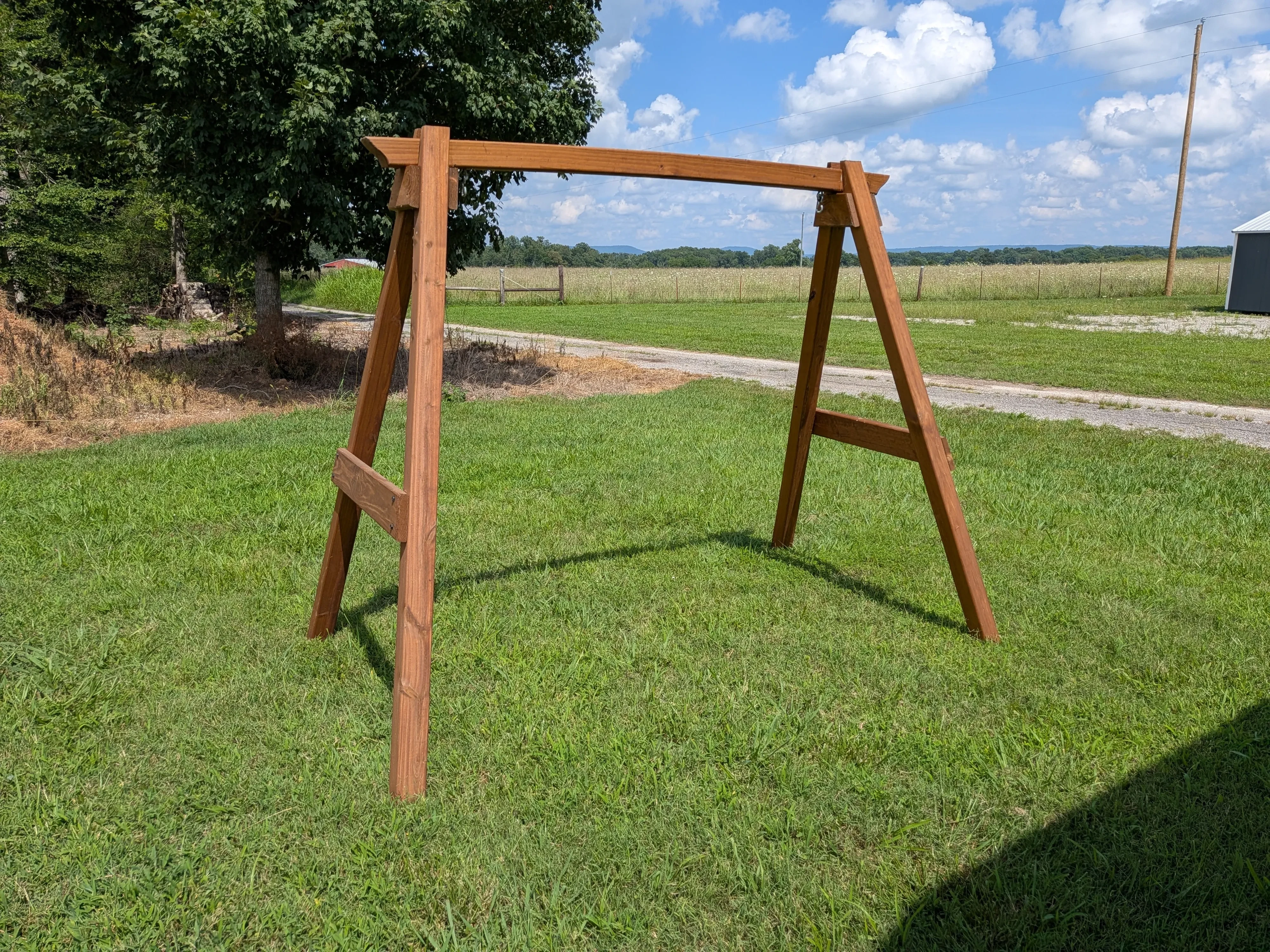 an a-frame structure in the grass. It is wooden and stained and sealed