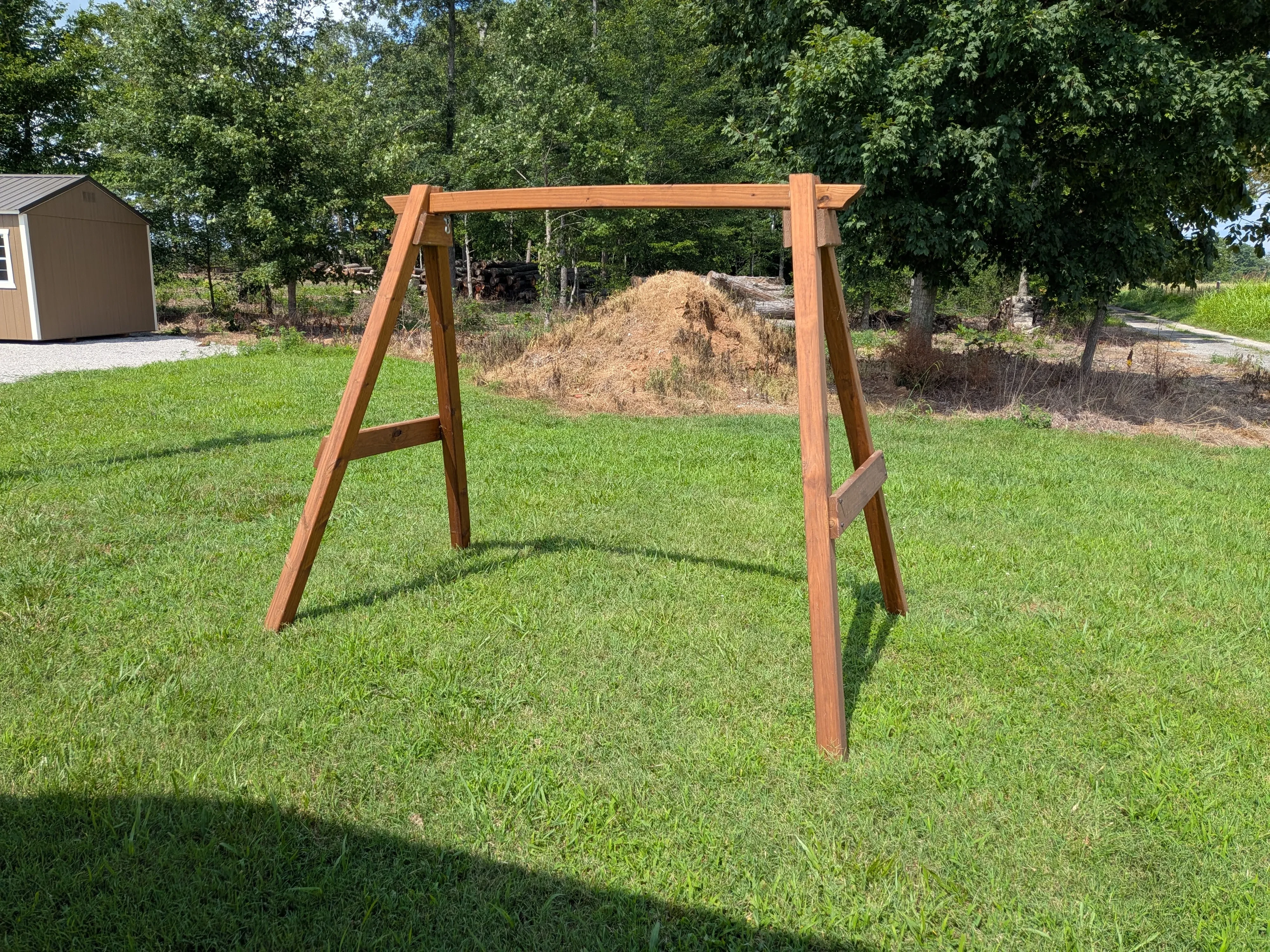an a-frame structure in the grass. It is wooden and stained and sealed