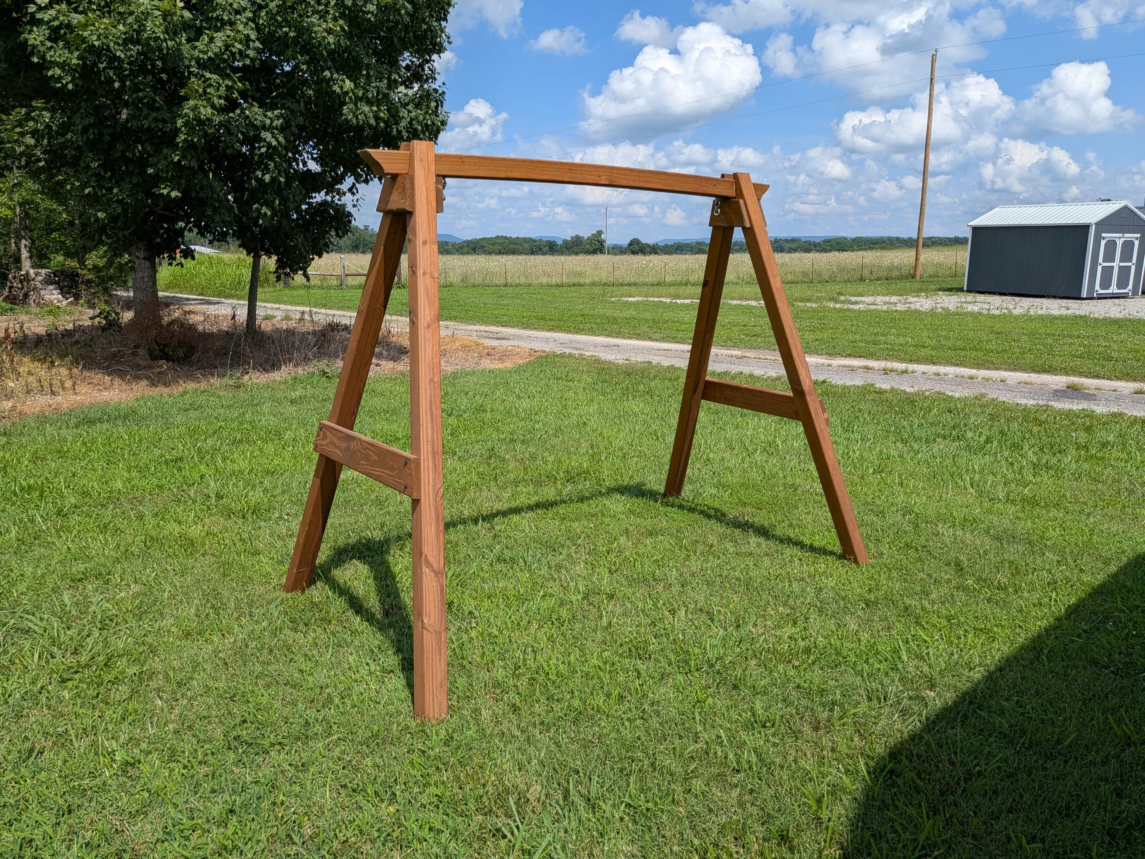an a-frame structure in the grass. It is wooden and stained and sealed