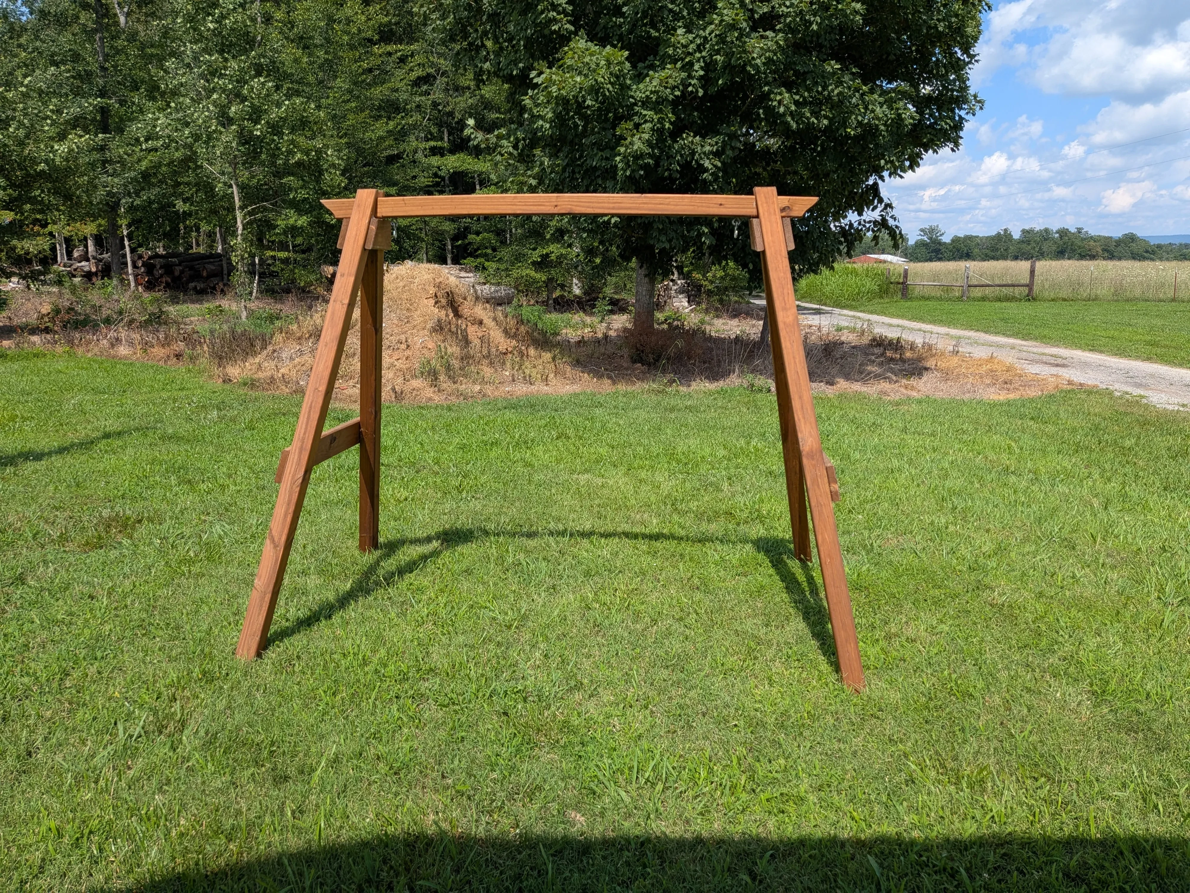 an a-frame structure in the grass. It is wooden and stained and sealed