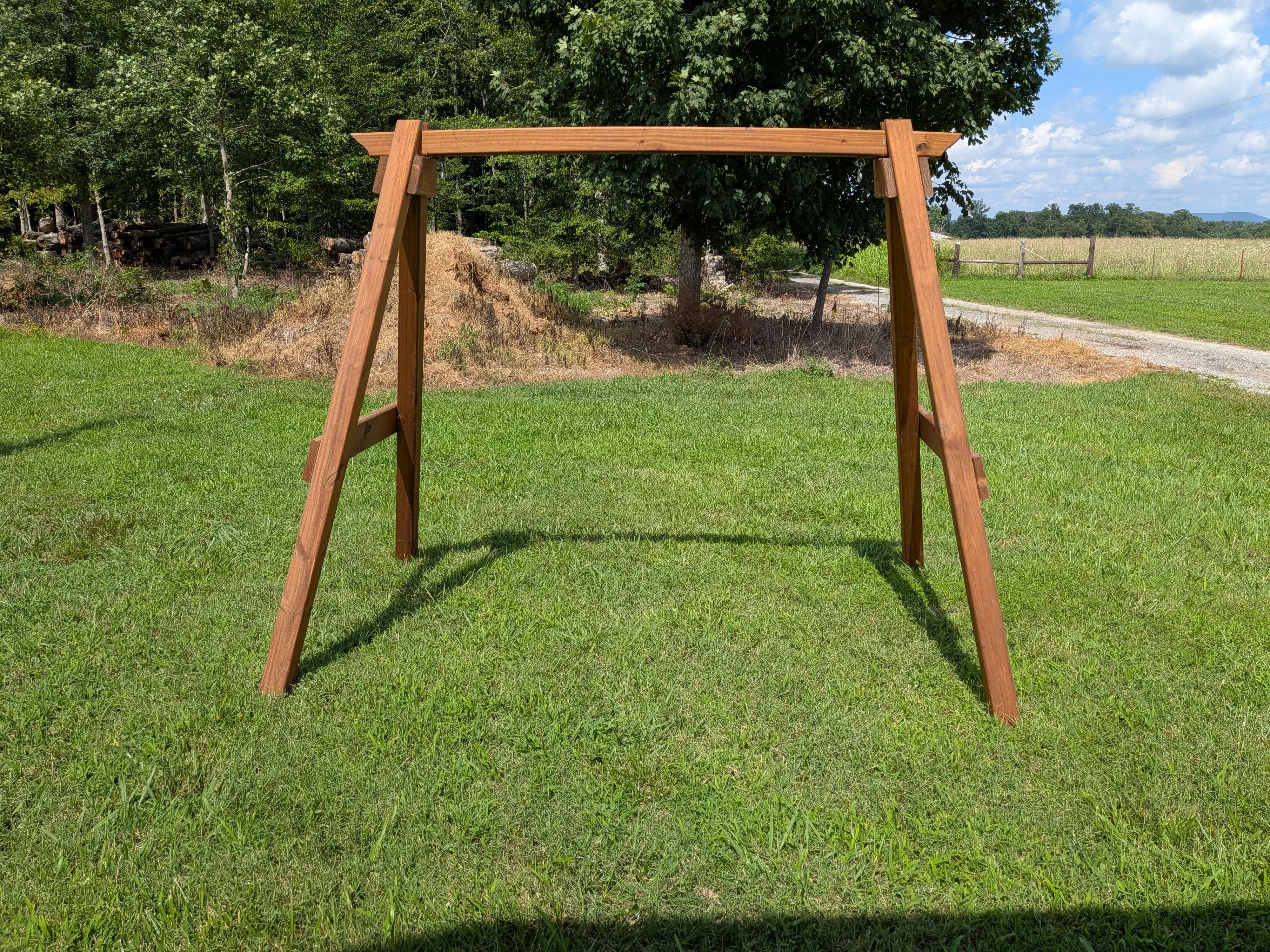 an a-frame structure in the grass. It is wooden and stained and sealed