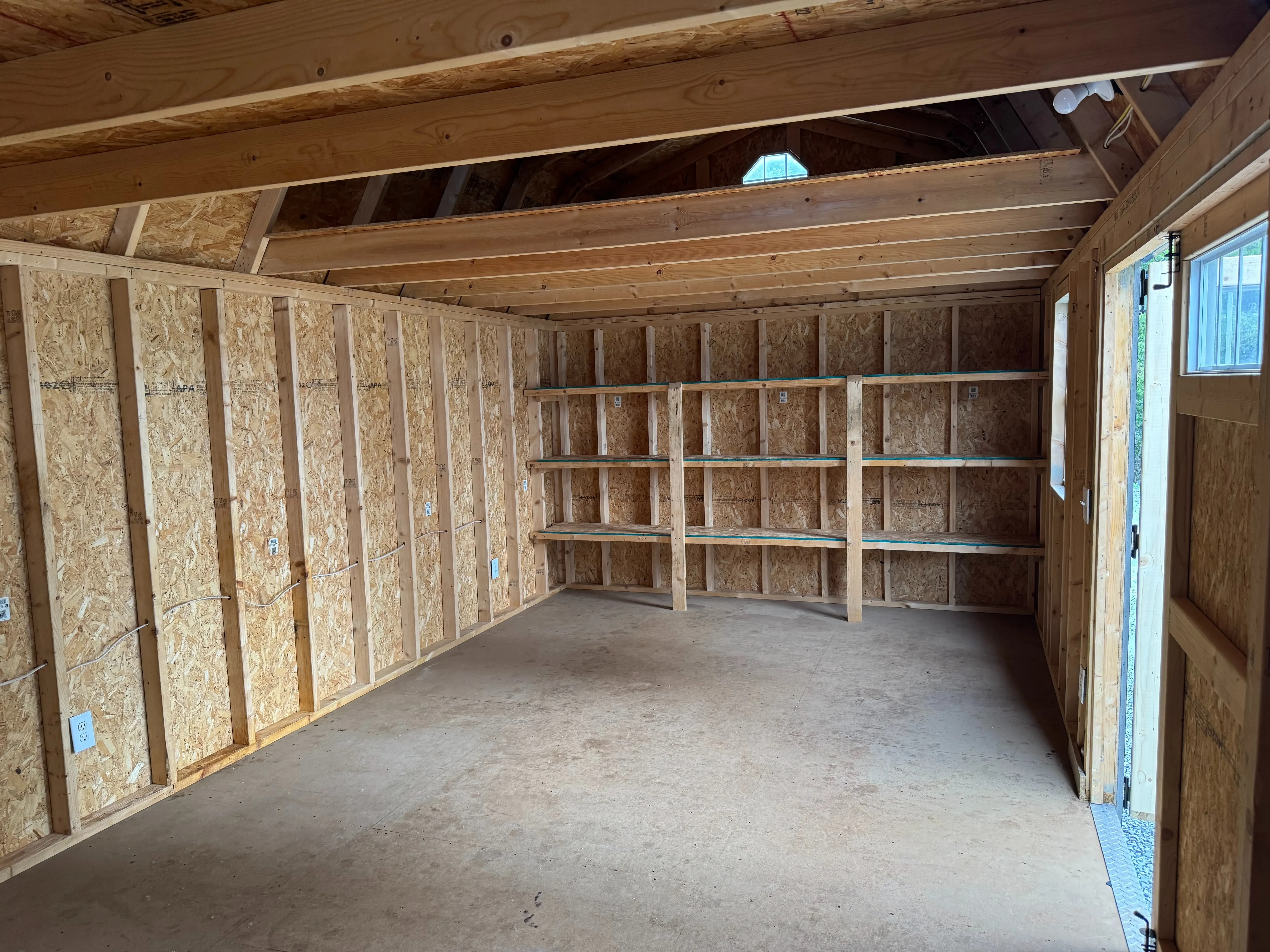 inside a large side lofted barn looking at the right wall. It has triple shelves and a loft above them