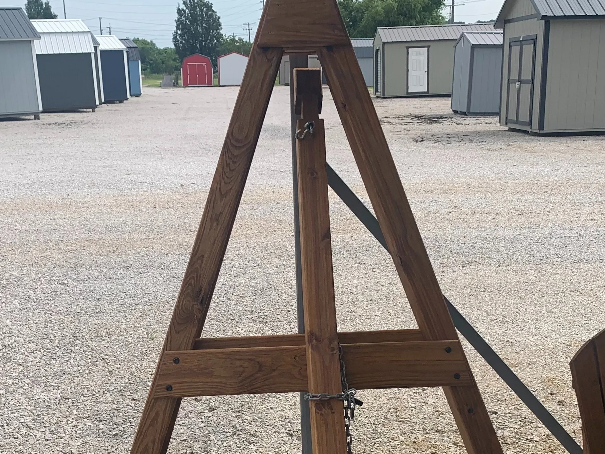a wood stained and sealed a-frame that is disassembled and leaning against a carport