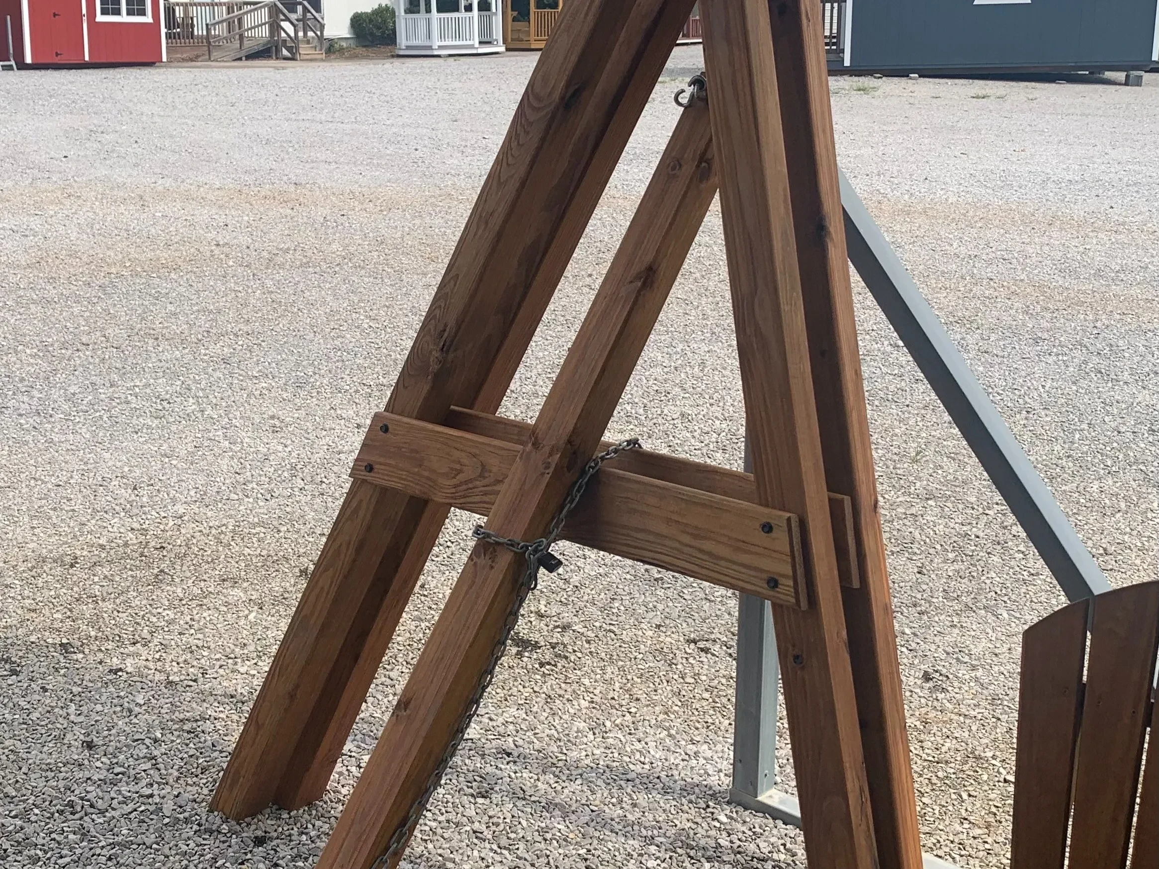 a wooden a-frame structure that is disassembled and leaning against a carport leg