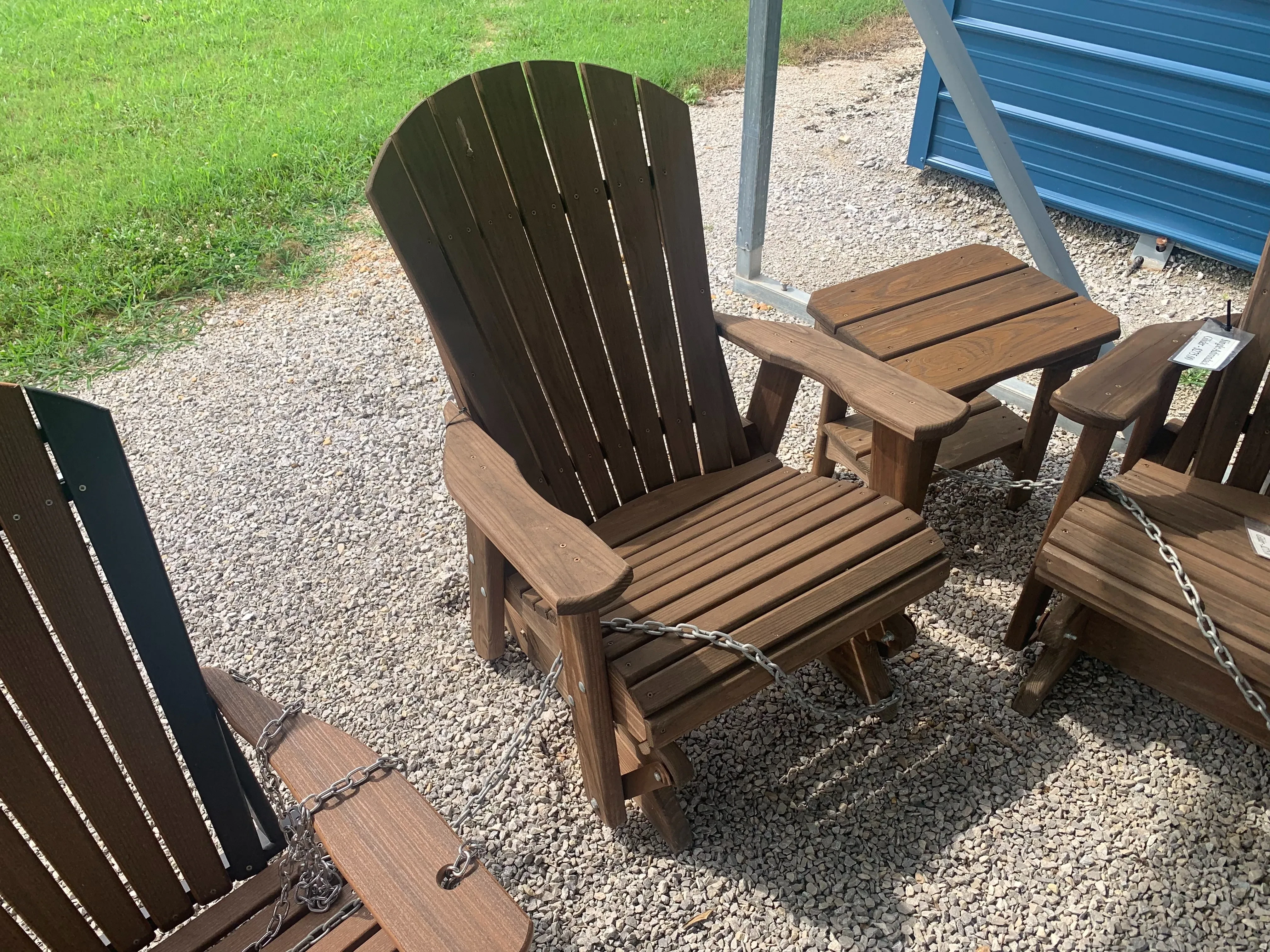 a wood stained and sealed chair that glides back and forth. It is sitting on gravel