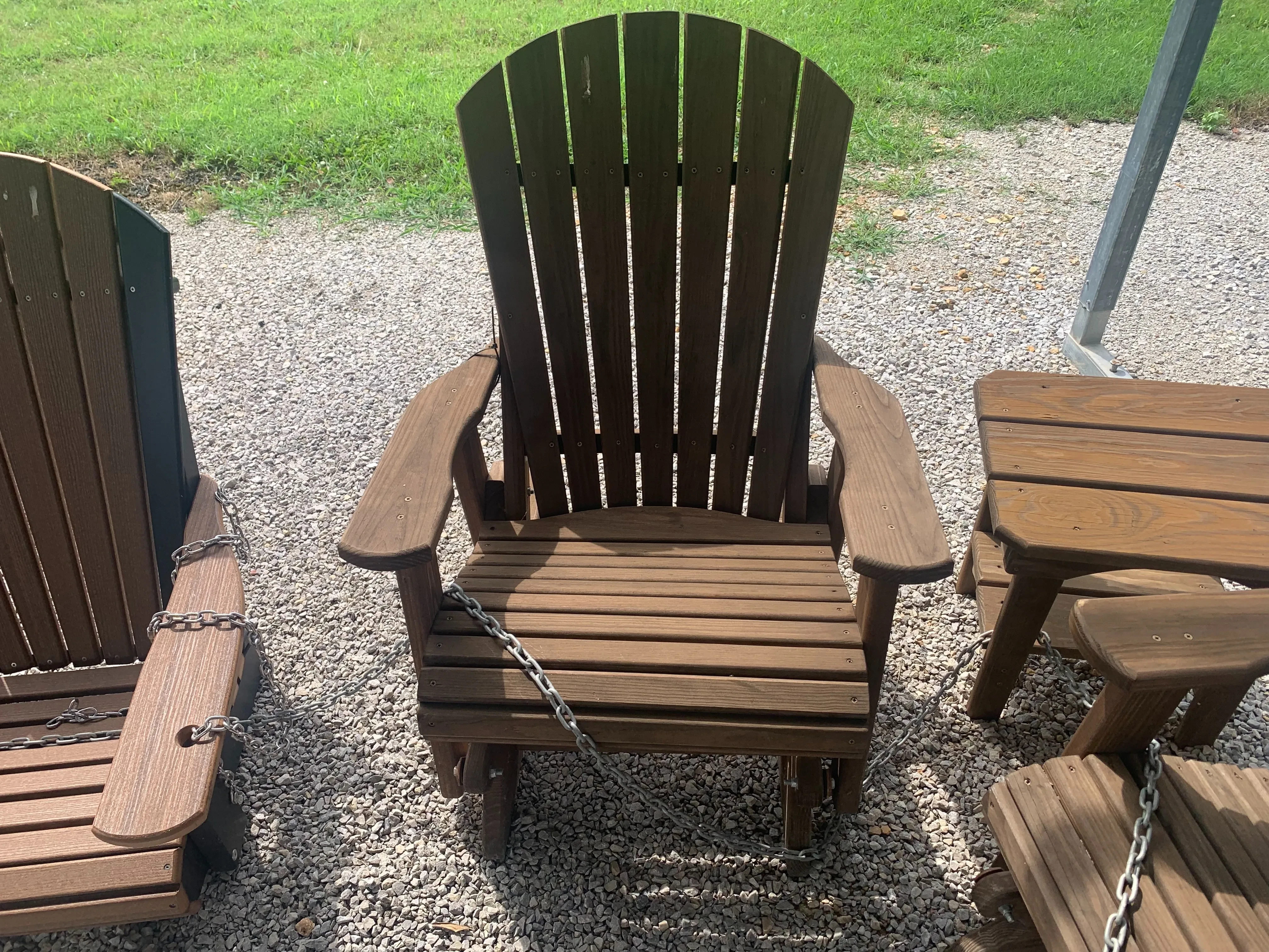 a chair sitting on the gravel. It is wood stained and sealed and can glide back and forth