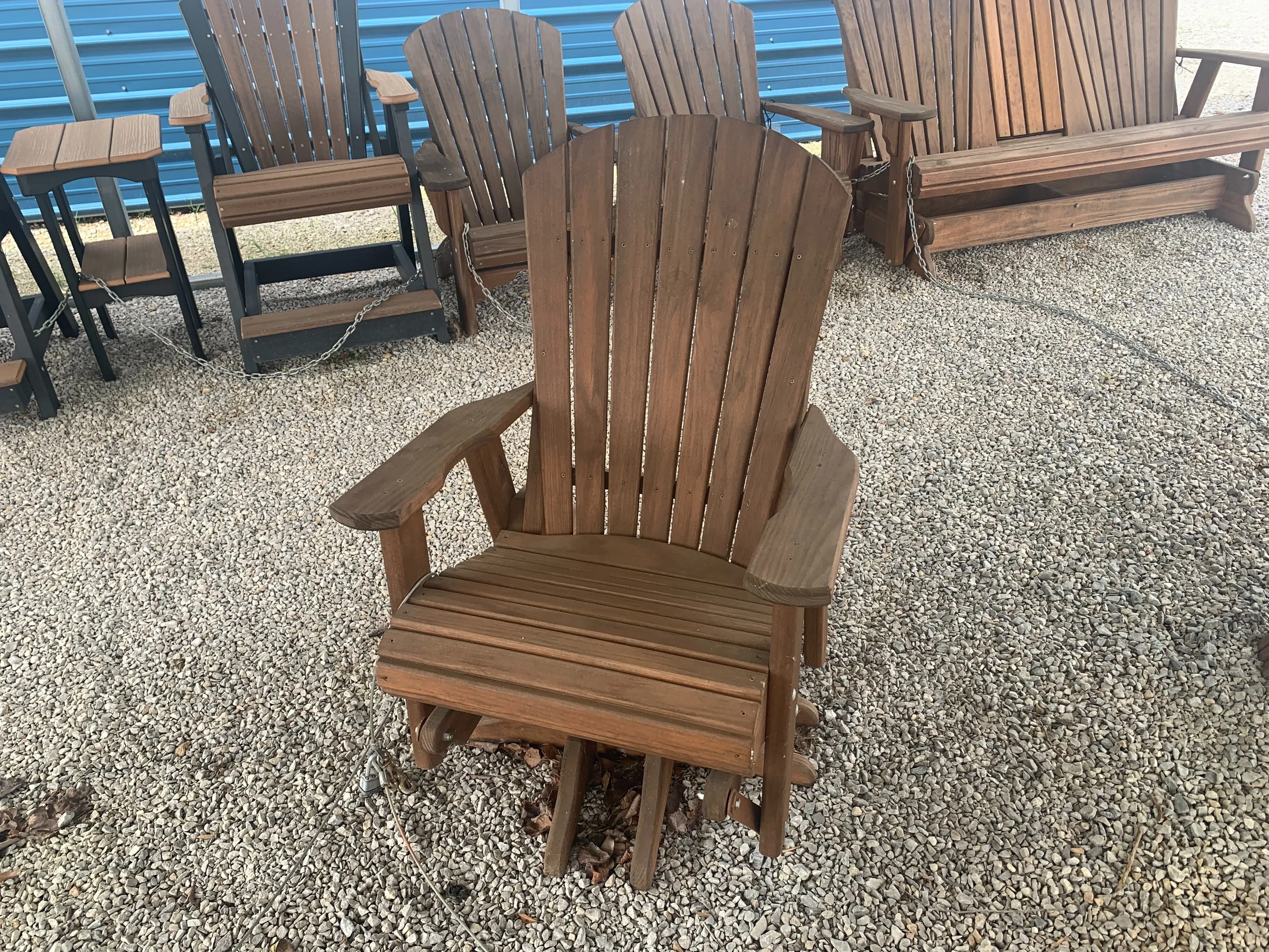 a wood stained and sealed chair that swivels and glides. It is sitting on gravel