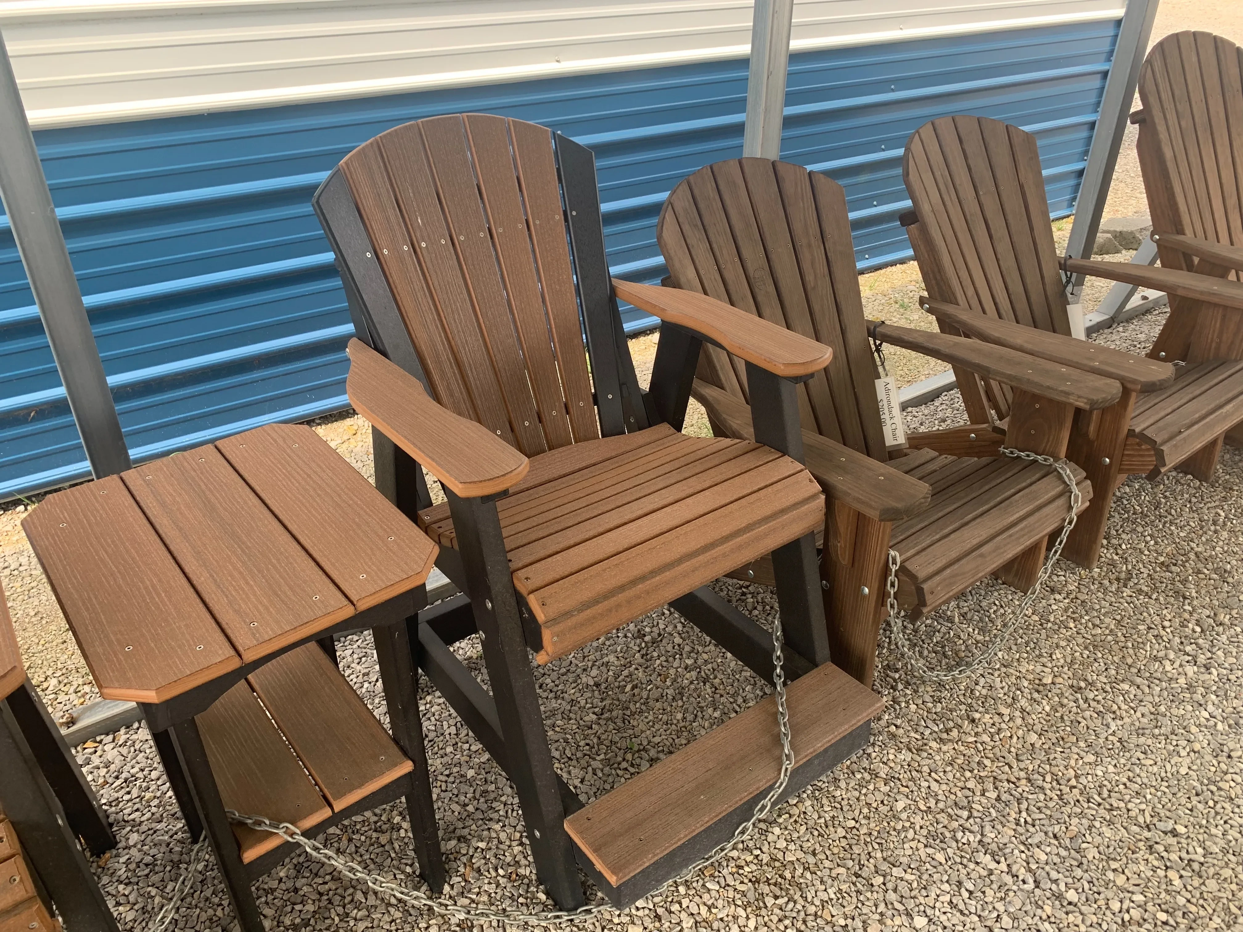 a chair sitting next to other chairs. It is made out of a polywood material and is brown and black