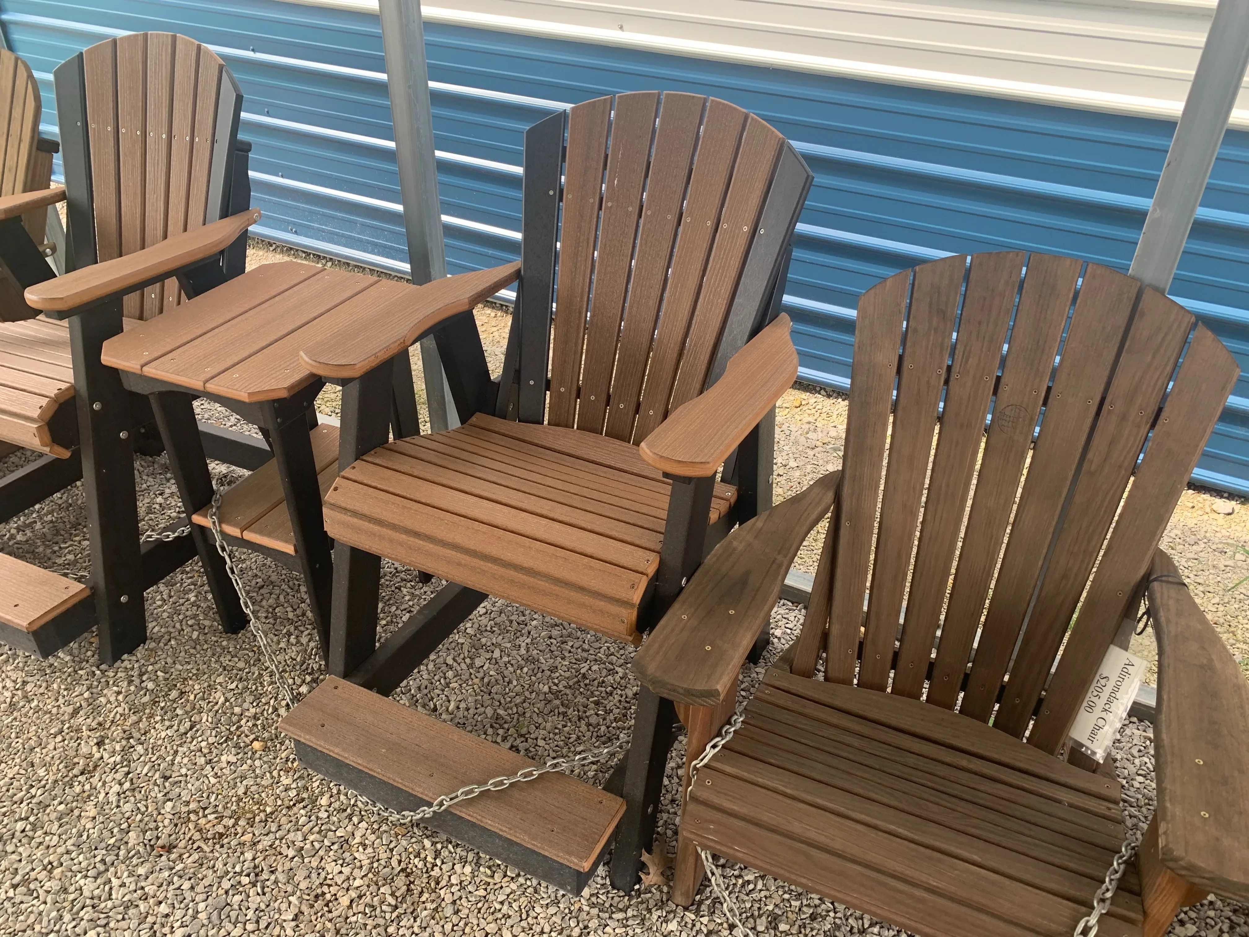 a brown and black chair sitting in the gravel. It has arm and foot rests. It is next to other chairs