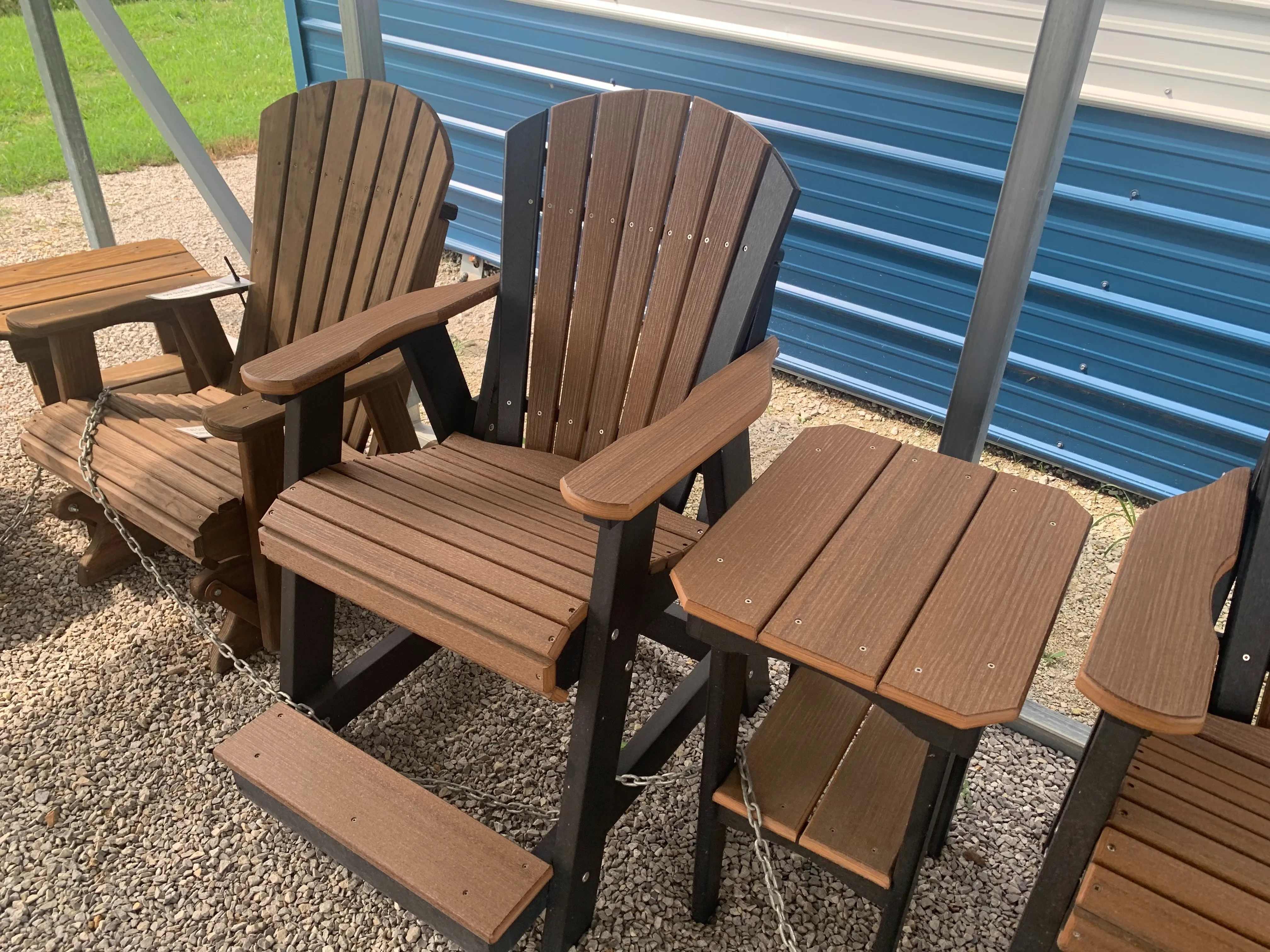 a black and brown chair sitting next to other chairs. It is sitting on gravel