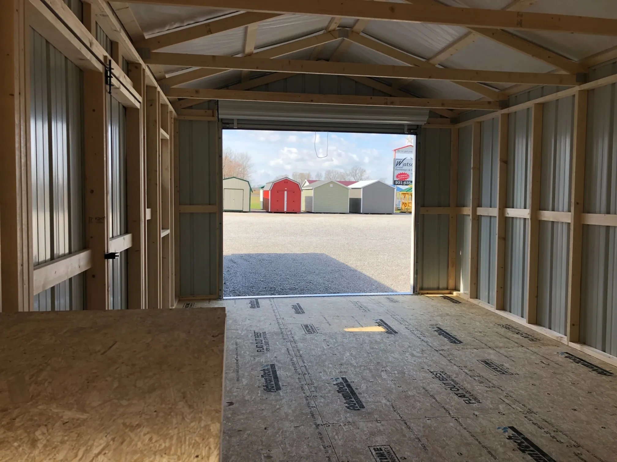 The inside of a metal garage looking through the rollup door that is open