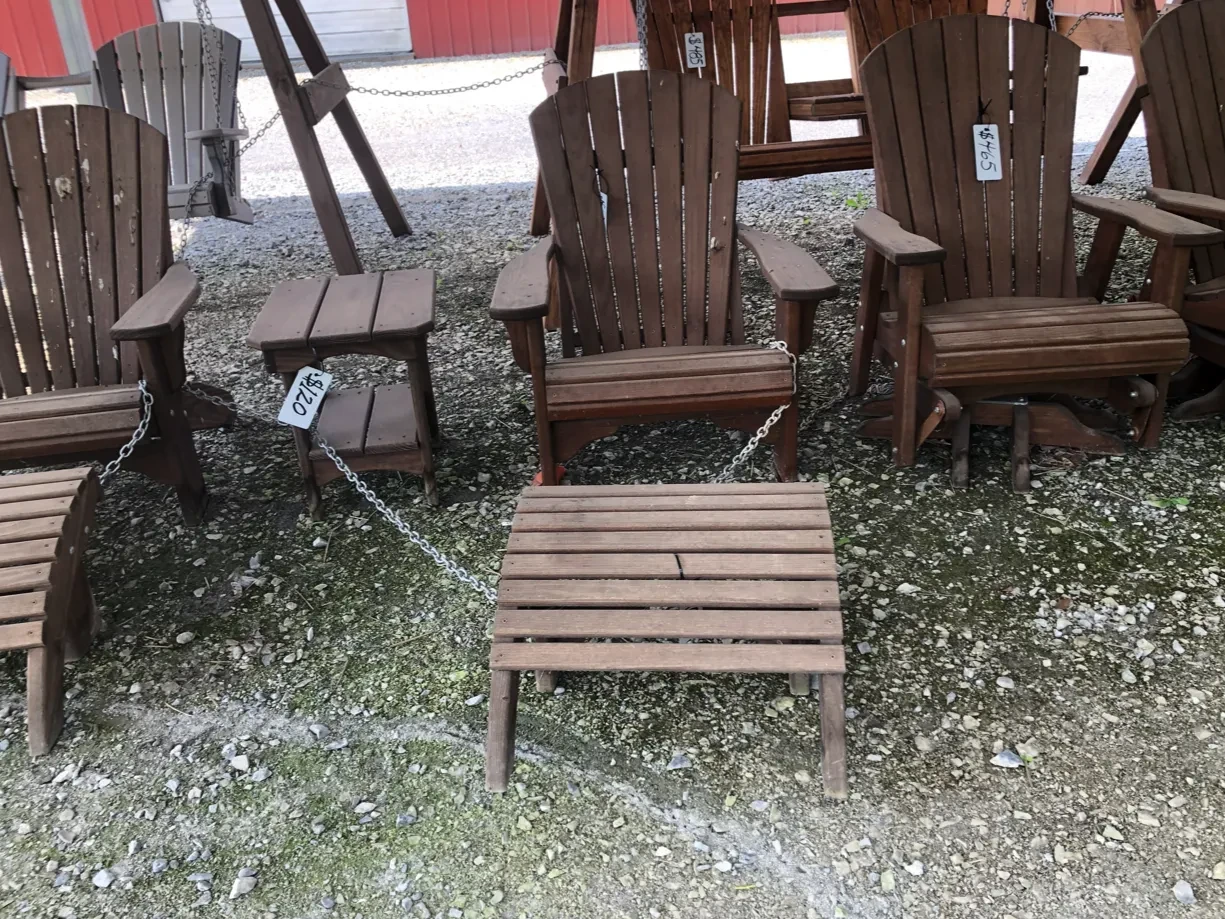 a footstool that is stained and sealed sitting on gravel and next to other wooden chairs