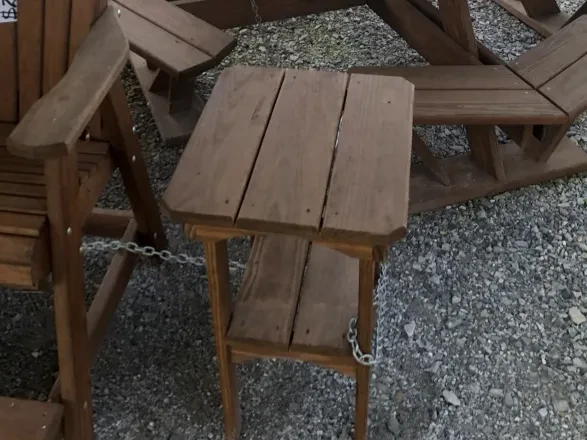 a wood stained and sealed table that is chained up next to other furniture