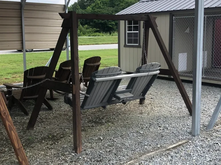 a polywood swing being held up by a wooden a-frame on gravel