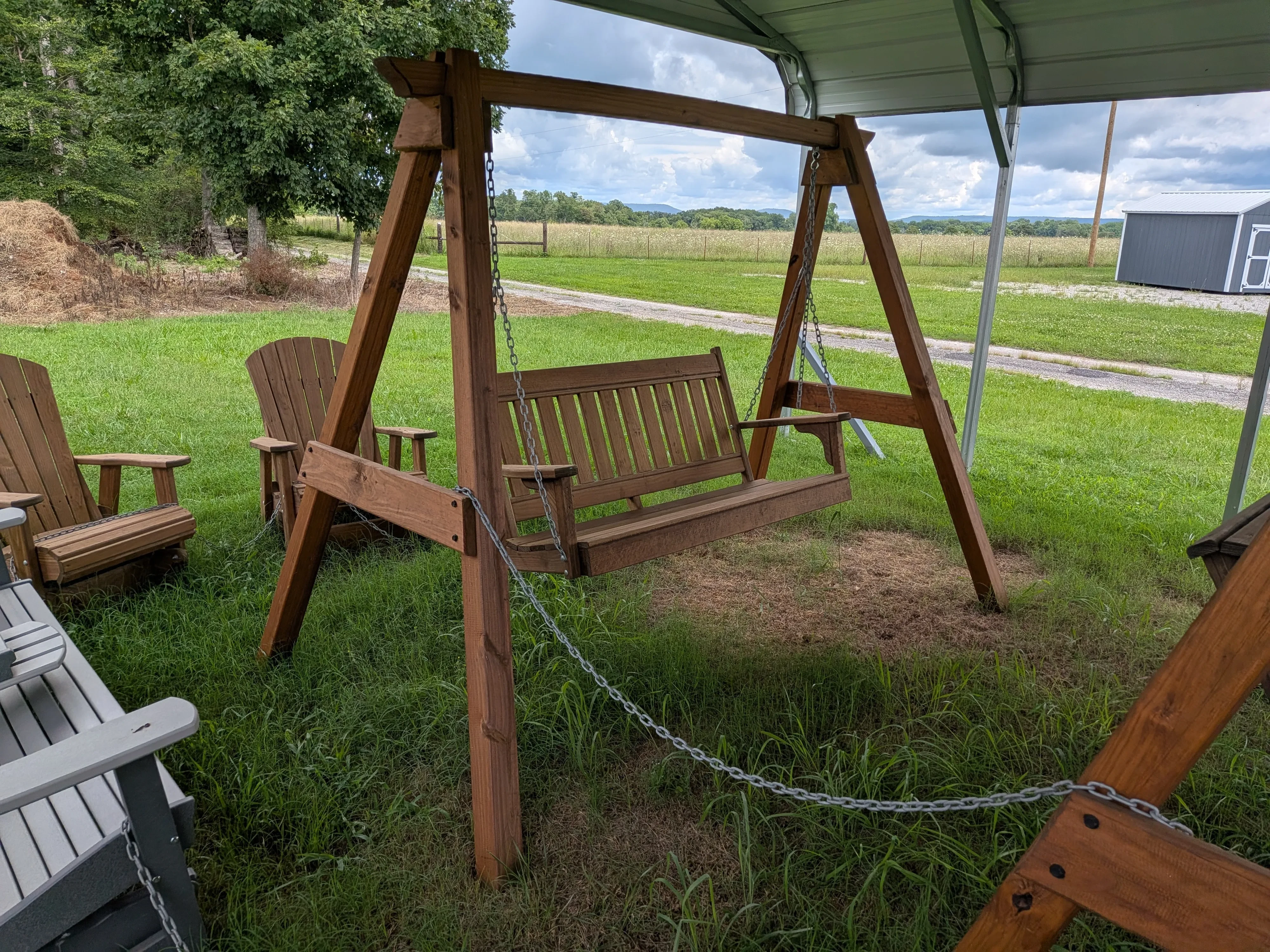 a wooden swing being held up by a wooden stained and sealed a-frame structure in the grass
