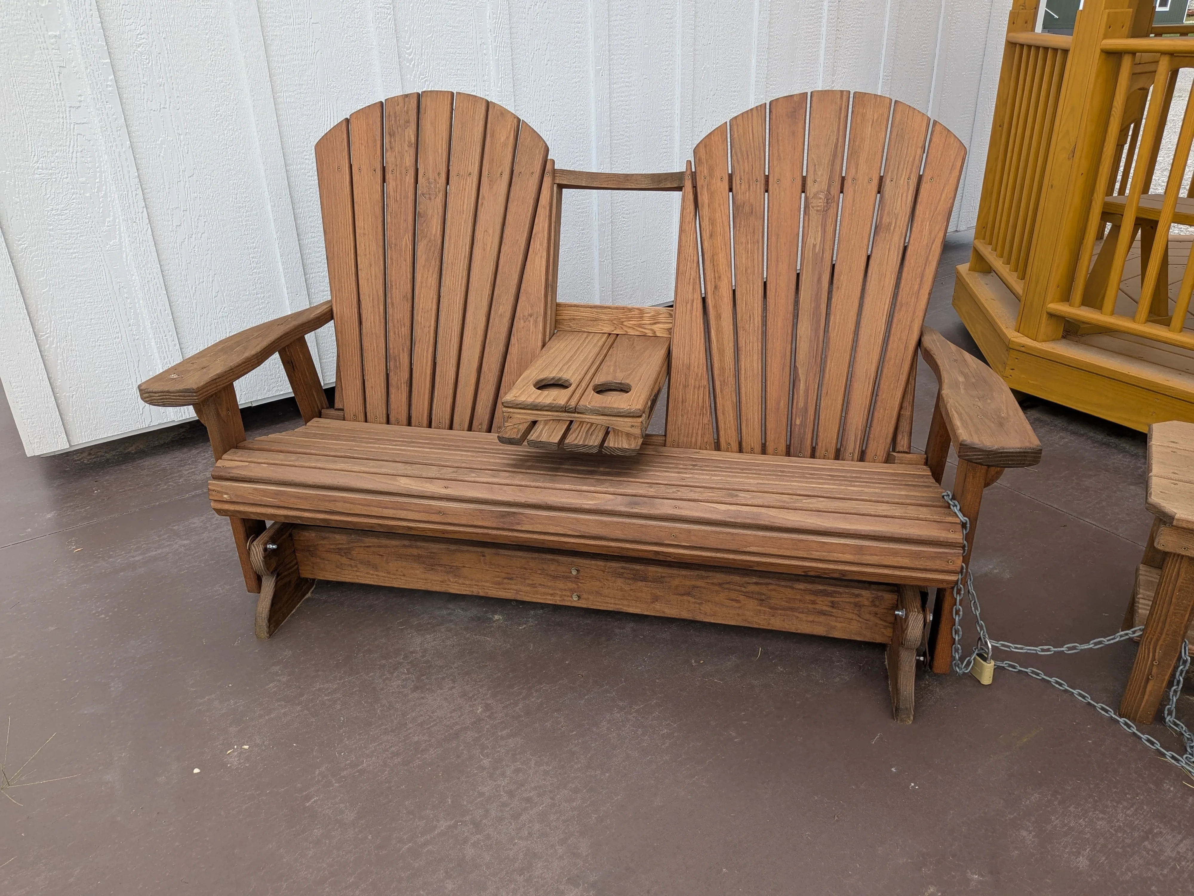 a wood stained and sealed bench that glades back and forth. It has a center console that flips up and down
