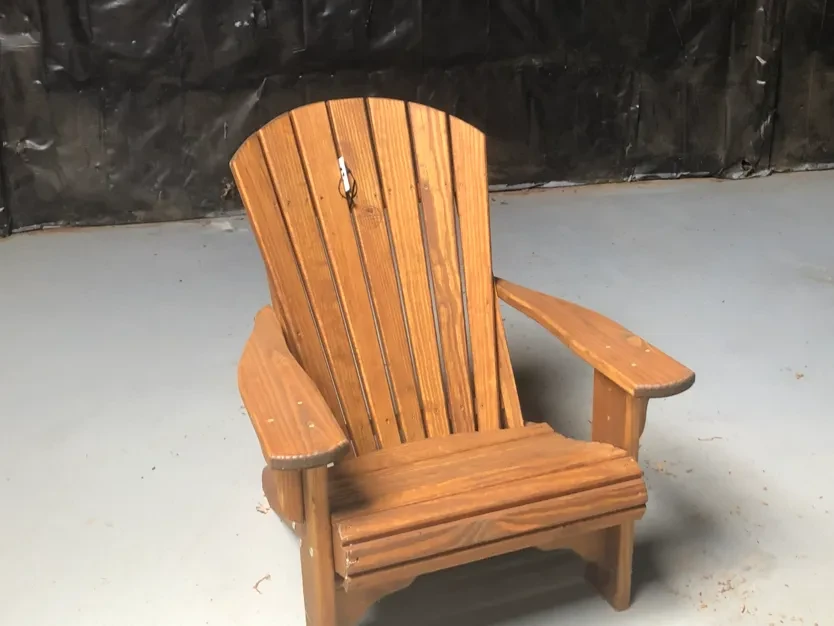 a chair sitting in a room by itself in front of a black wall. It is stained and sealed