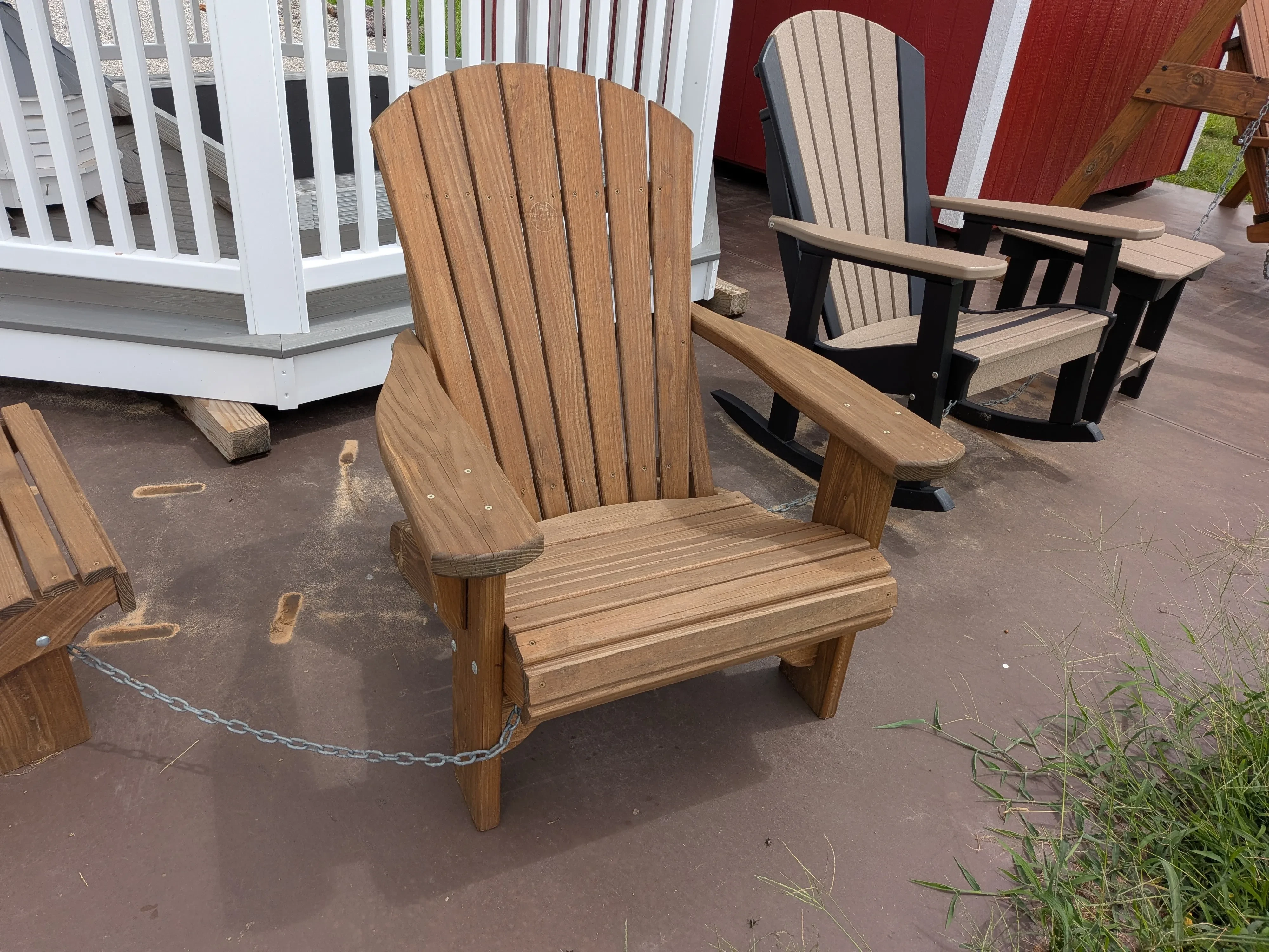 a wooden chair sitting next to other chairs on a concrete pad. It is stained and sealed