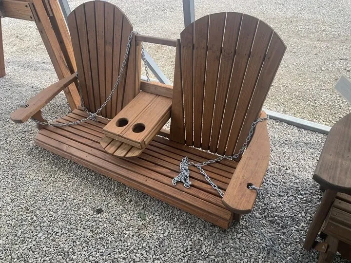 a wood swing sitting on the gravel. It is stained and sealed