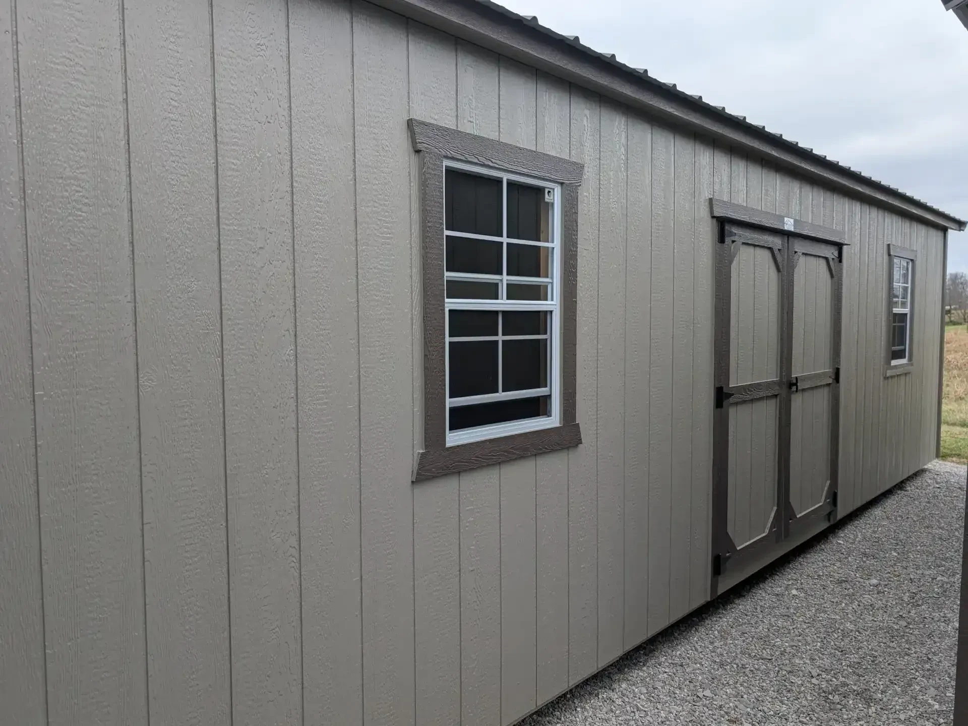 The side of a shed showing double doors and 2 windows
