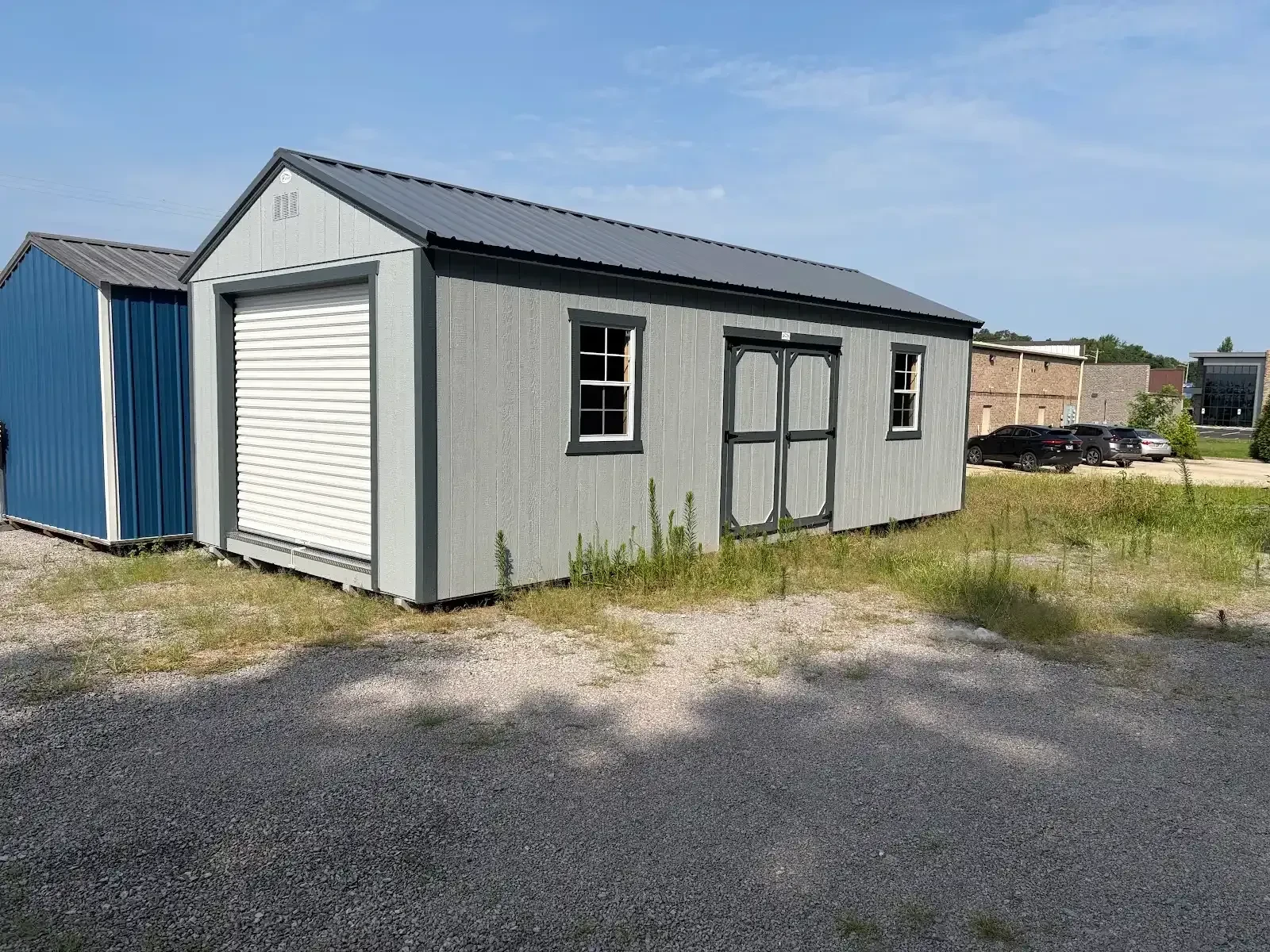 a wood garage shed with a rollup door in the front and double doors and windows on the right side