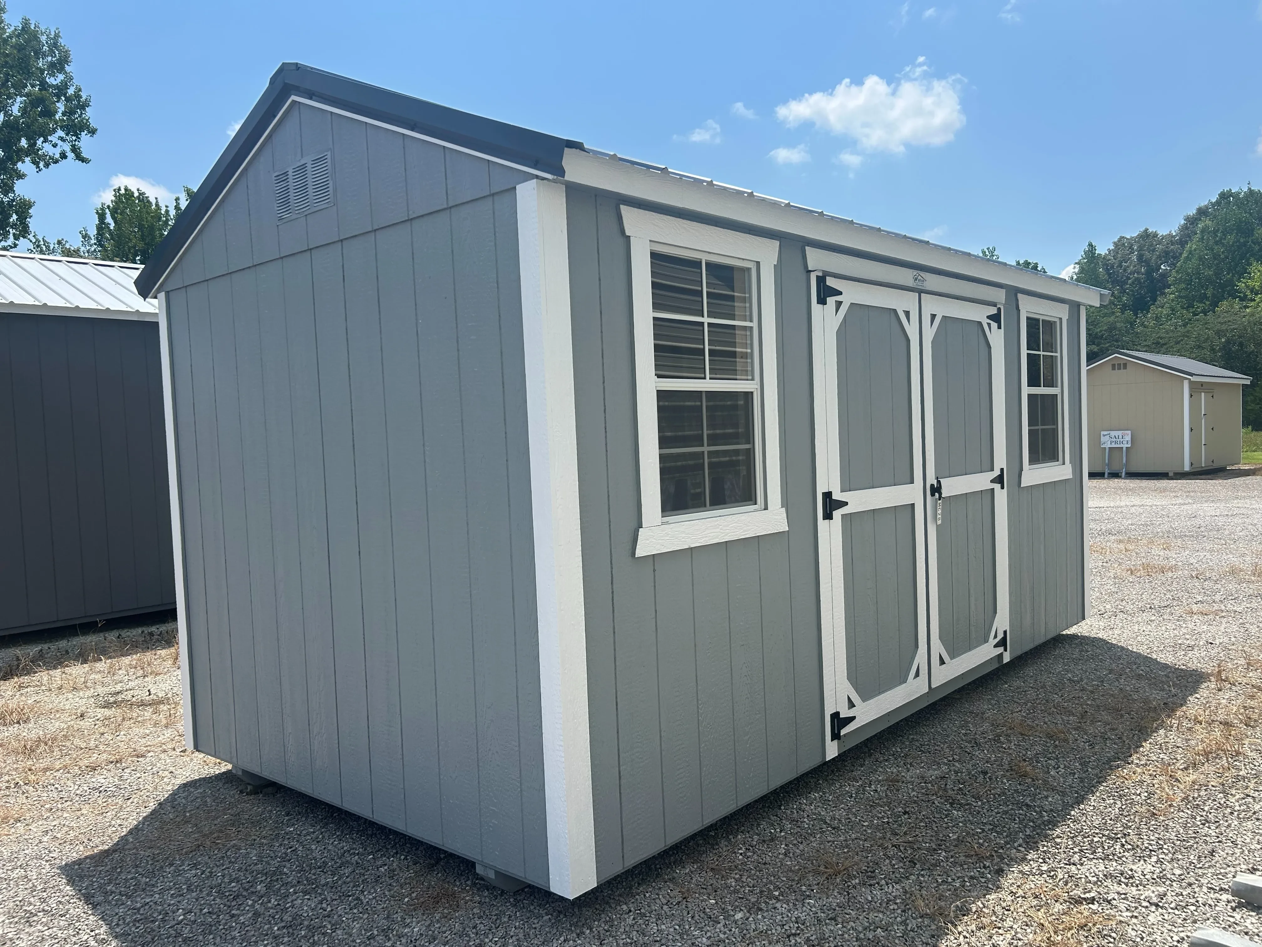 The side view of an 8x16 classic wood garden shed in light gray with slate gray roof.