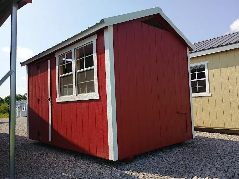 Outside of 8x12 painted chicken coop with metal roof, with single door and two windows.