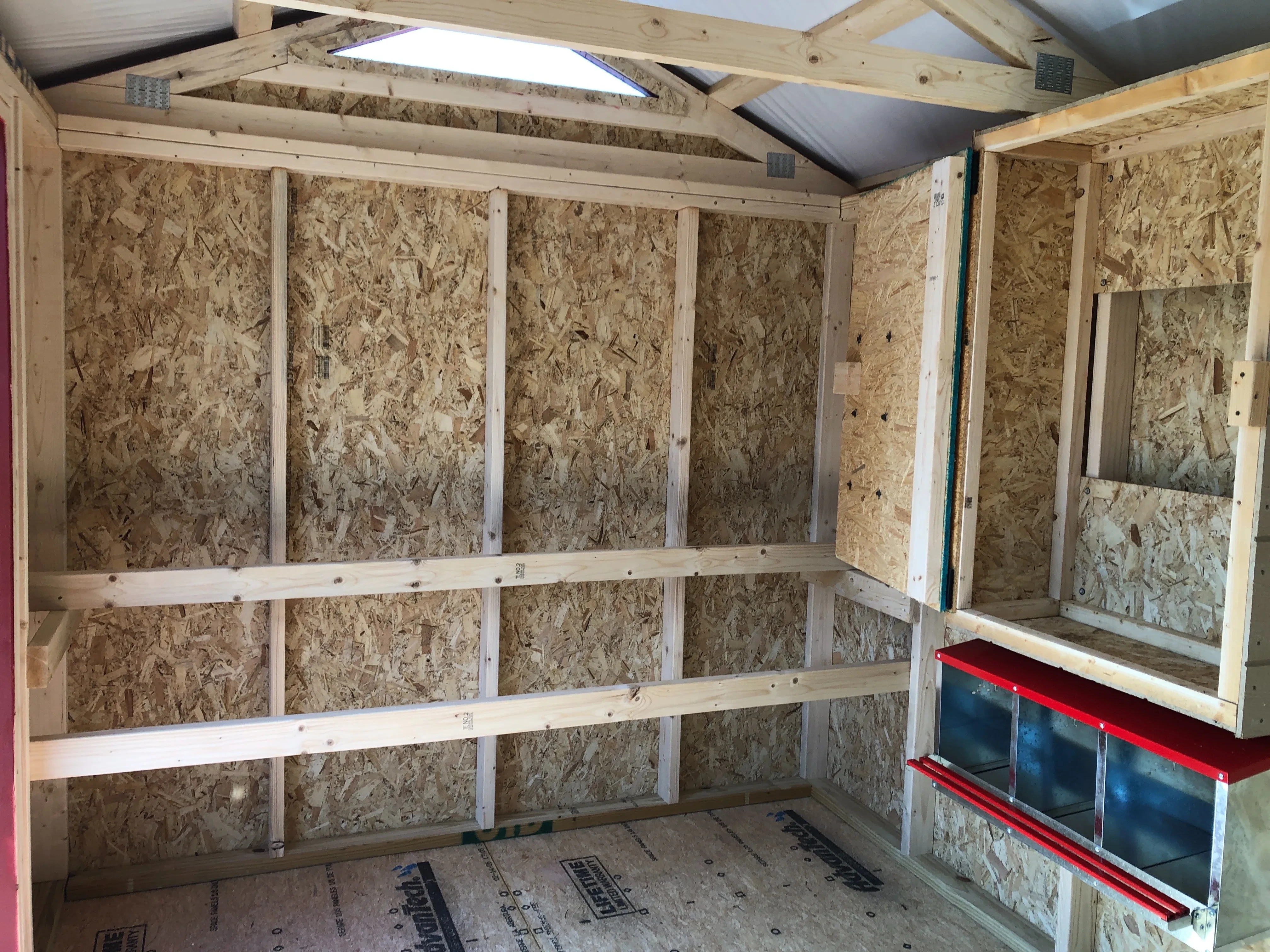 interior of 8x12 chicken coop showing a storage cabinet, roosting bars and nesting boxes