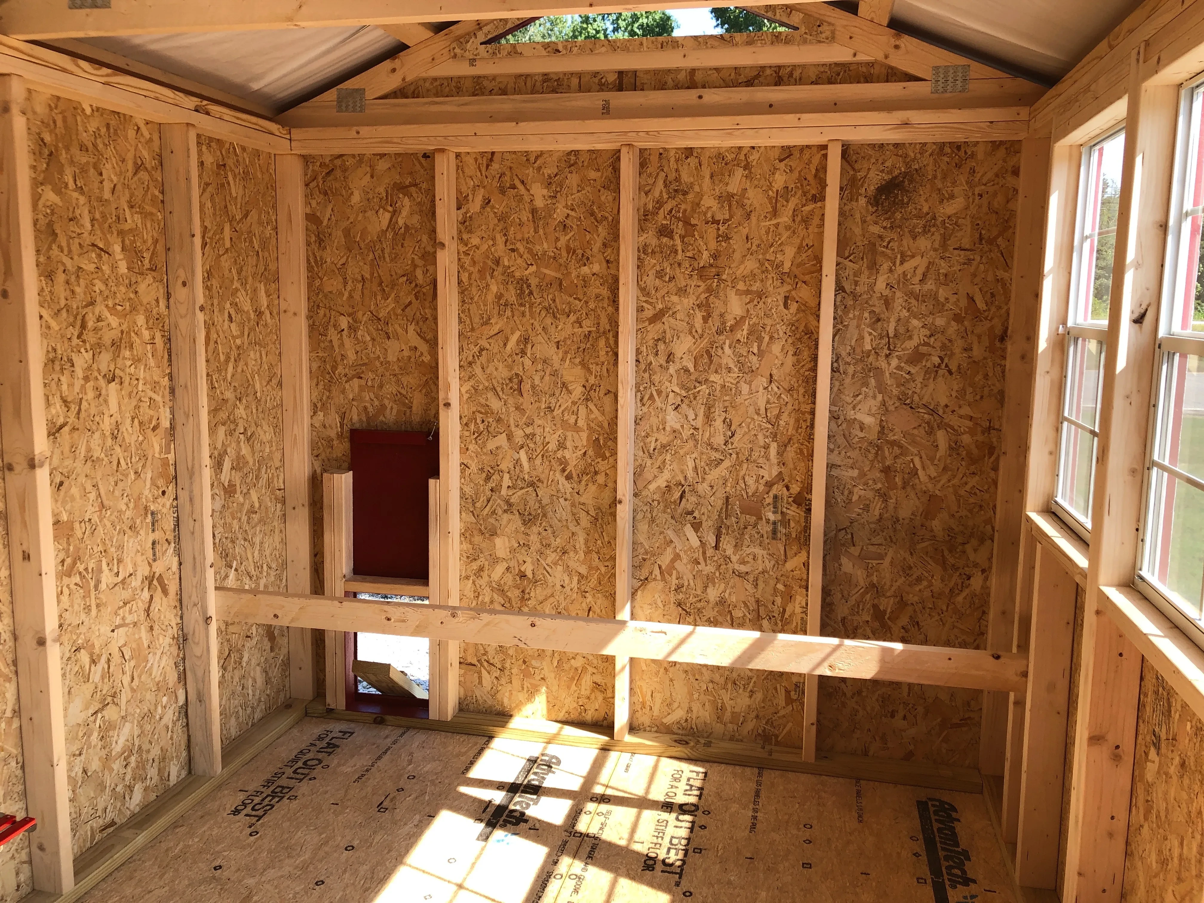 interior of 8x12 chicken coop showing a roosting bar and the chicken exit and entry door