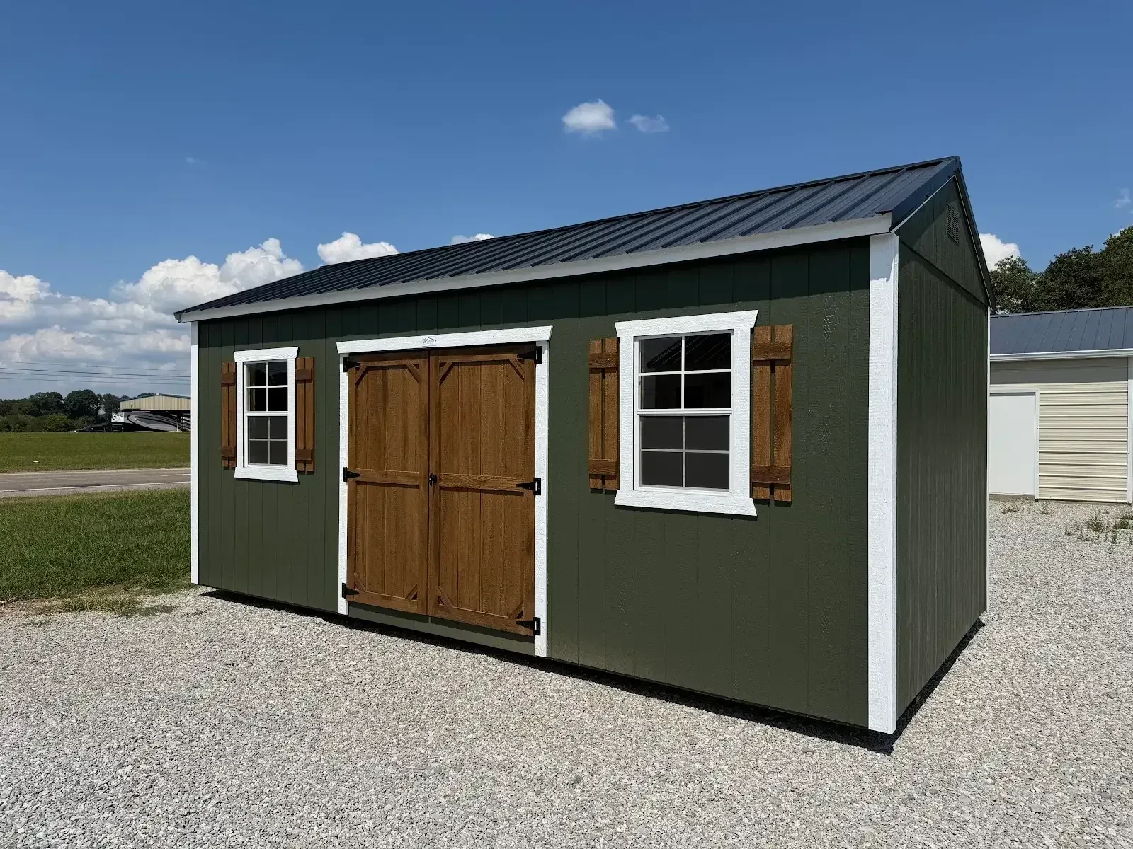 A classy dark green garden shed with stained wood double doors and shutters with a window on each side of the double doors