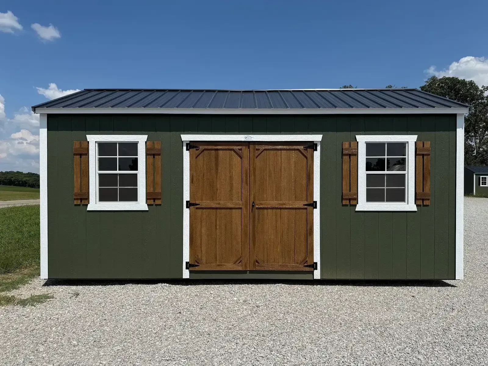 front of a dark green garden shed with stained wood double doors and shutters with a window on each side of the double doors