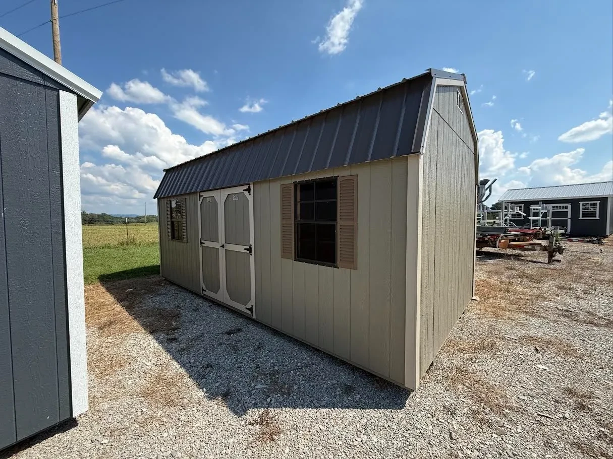 Outside of a used side lofted barn with double doors and two windows in the side