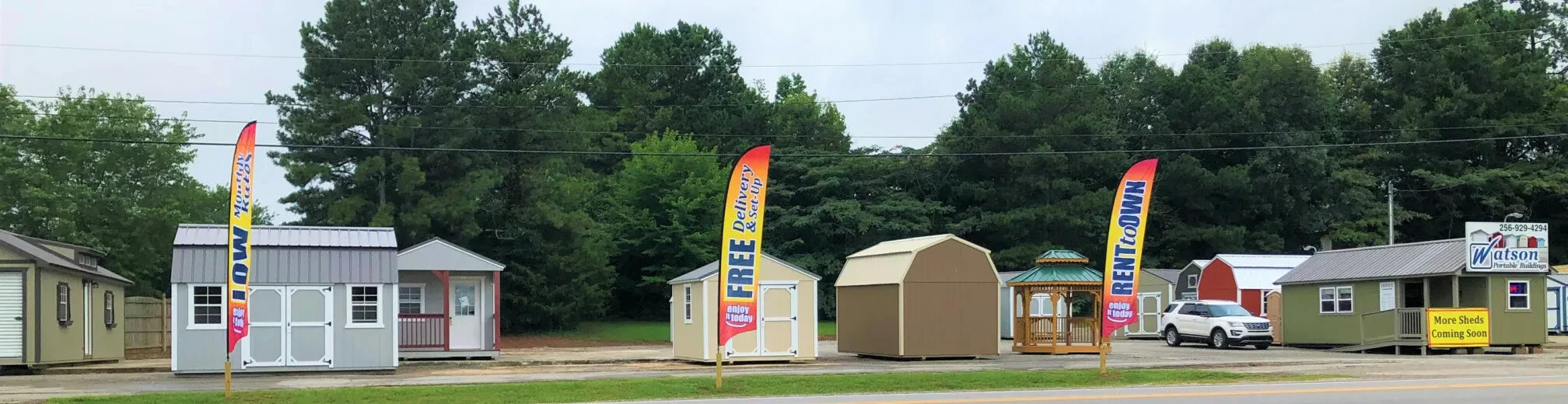 sheds and colorful banner flags at the harvest sales lot as seen from the road