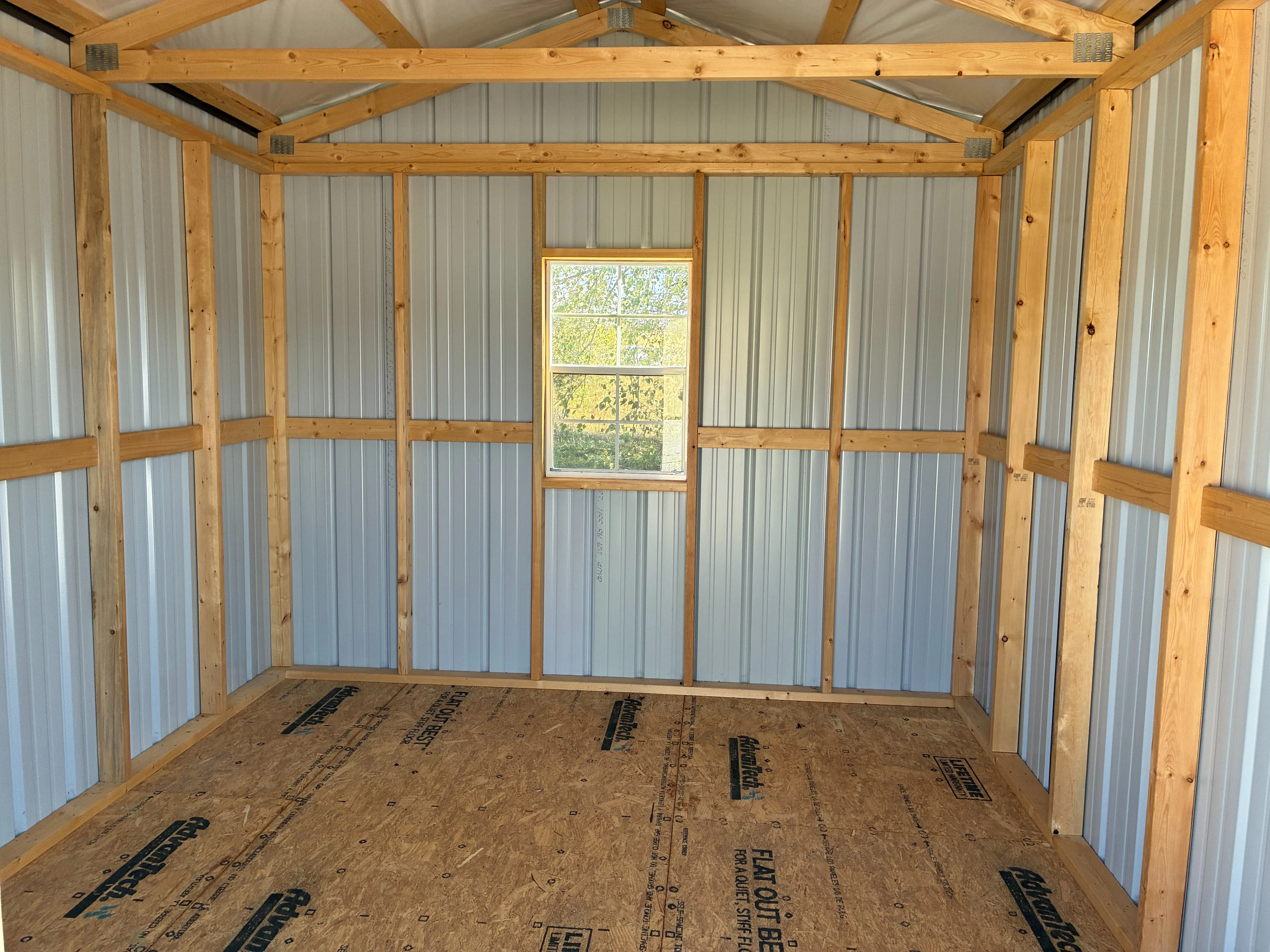 inside a metal utility shed looking at the back wall which has a window in the middle of it