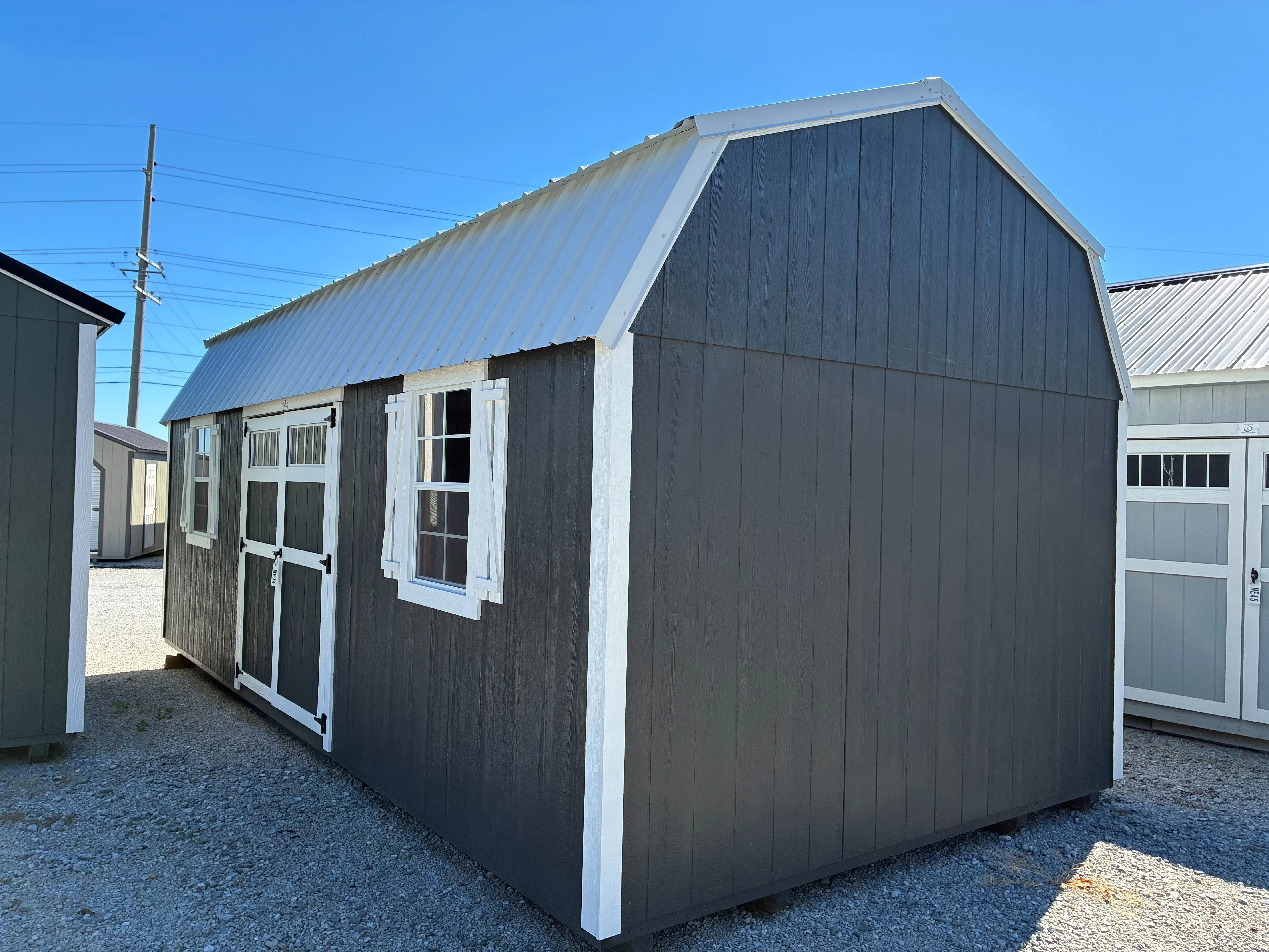 Exterior of 12x24 Classic Wood Side Lofted Barn showing double doors with transom window and two 2'x3' windows with shutters