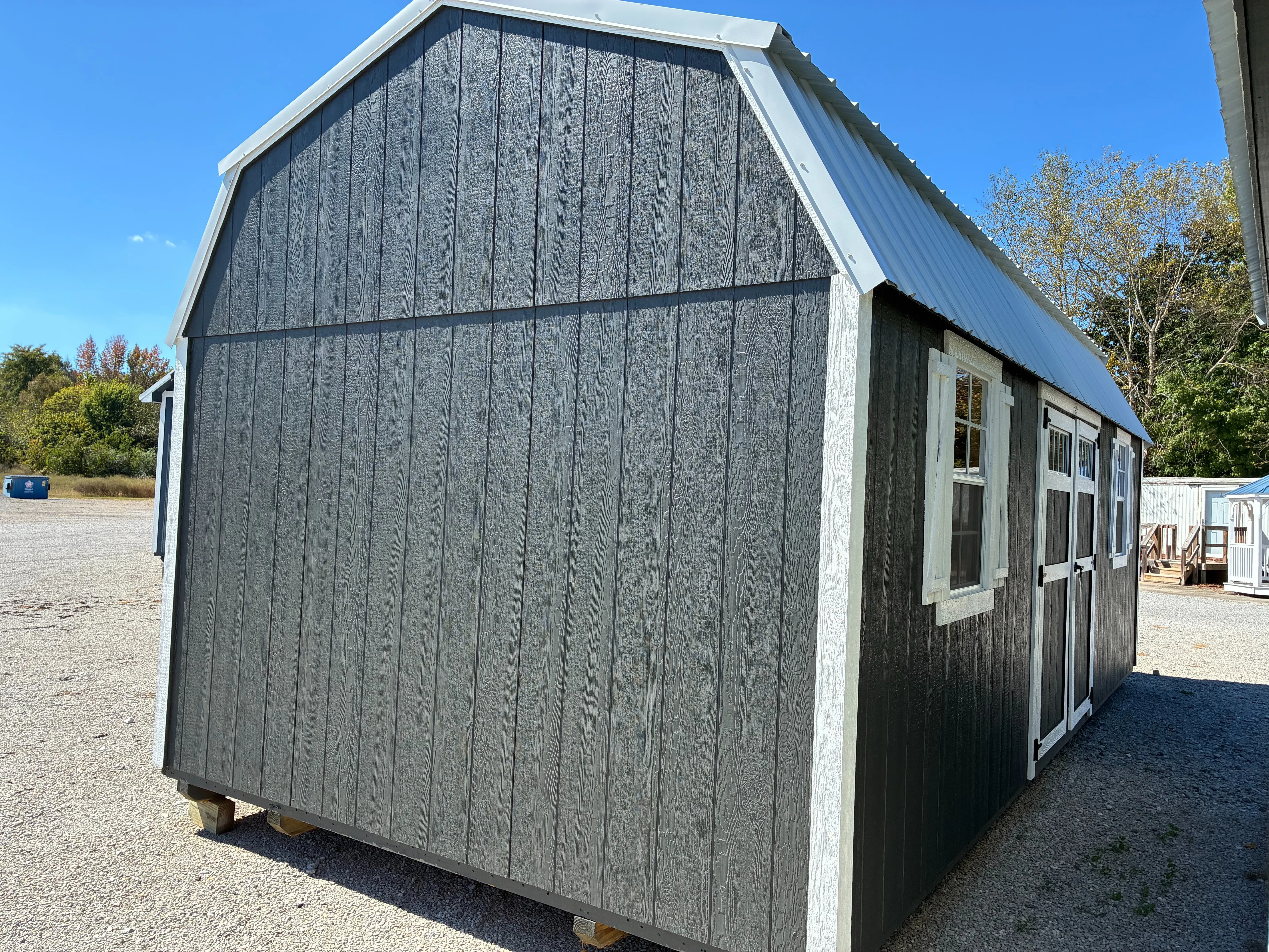 Exterior of 12x24 Classic Wood Side Lofted Barn showing double doors with transom window and two 2'x3' windows with shutters