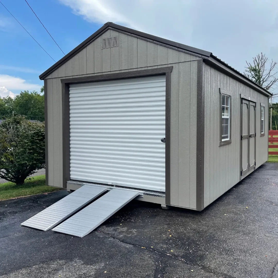 a large garage shed with a garage door and ramp on the end and double doors and two windows on the side