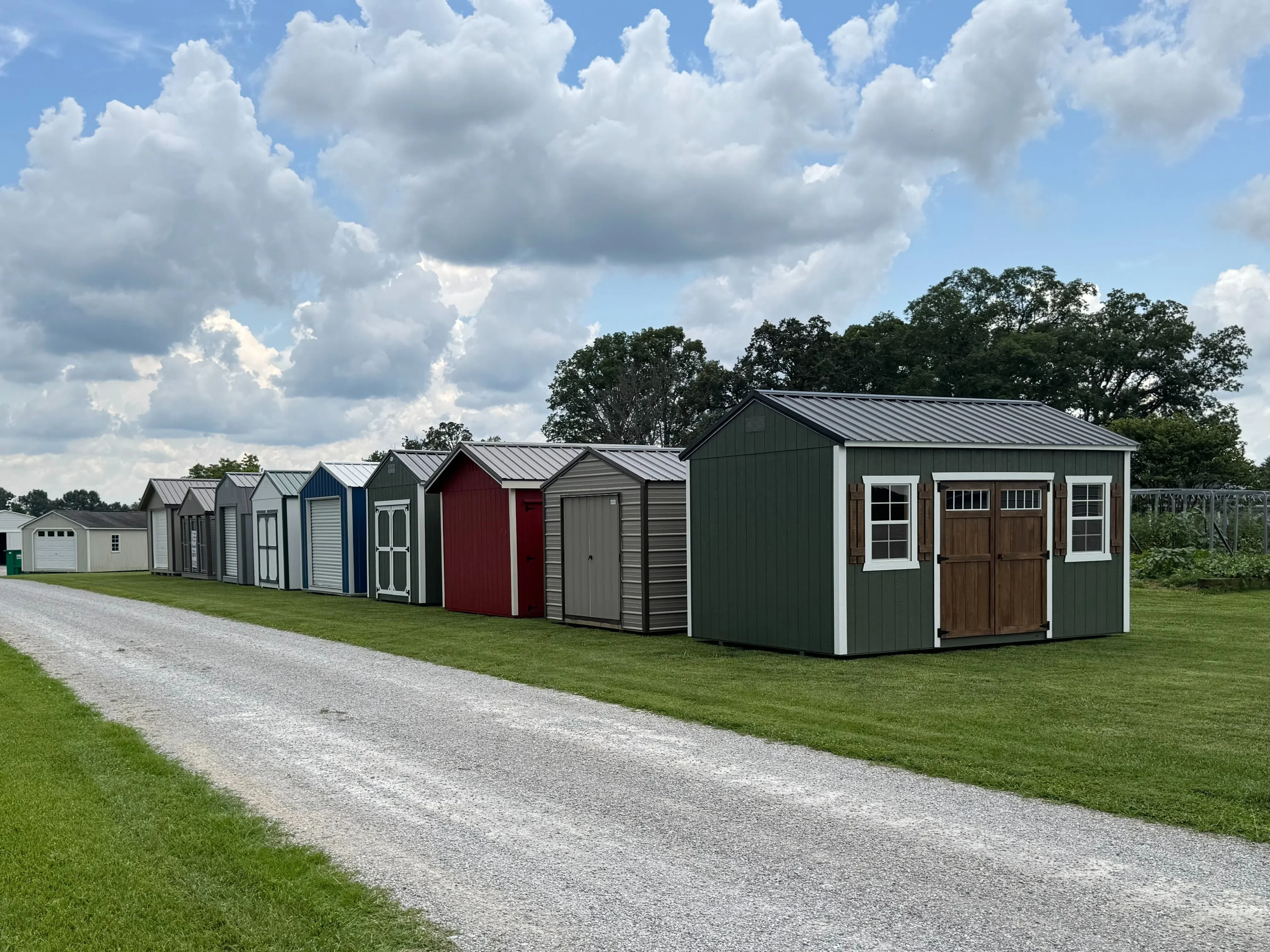 colorful row of sheds sitting by a gravel drive in green grass