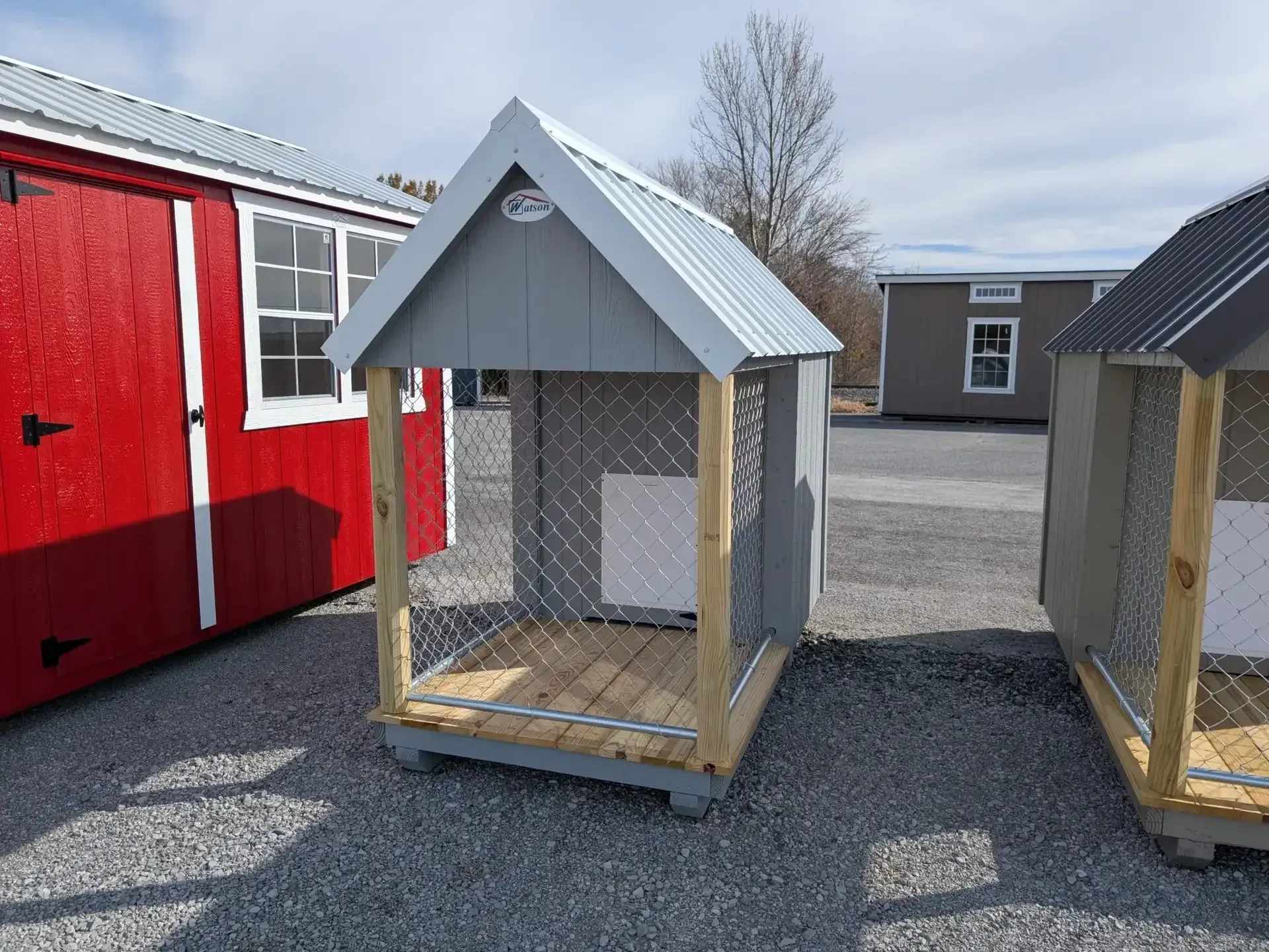 A gray dog kennel with a chain-link fenced in run