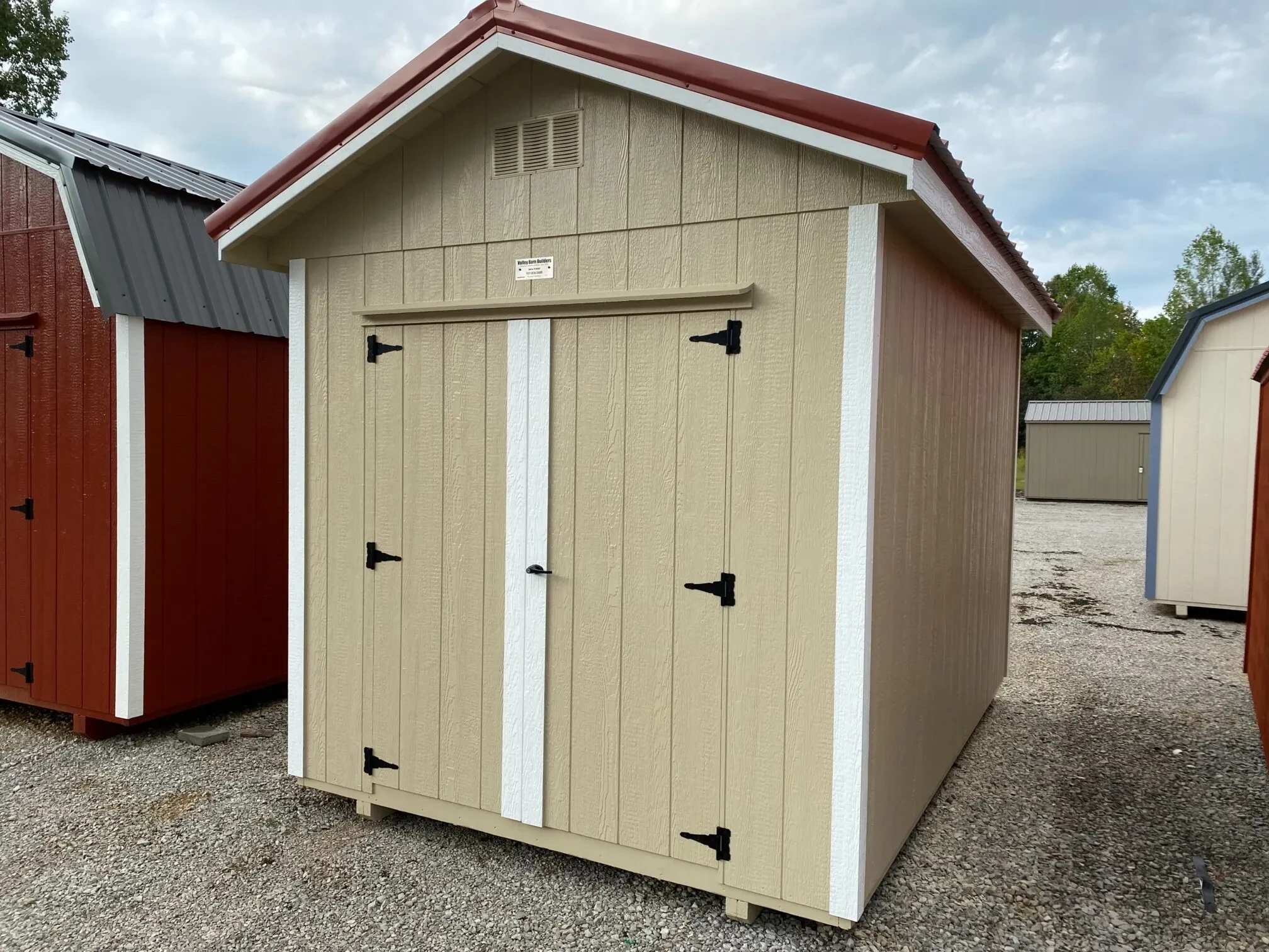 A stone colored shed with double doors and a vent on the front