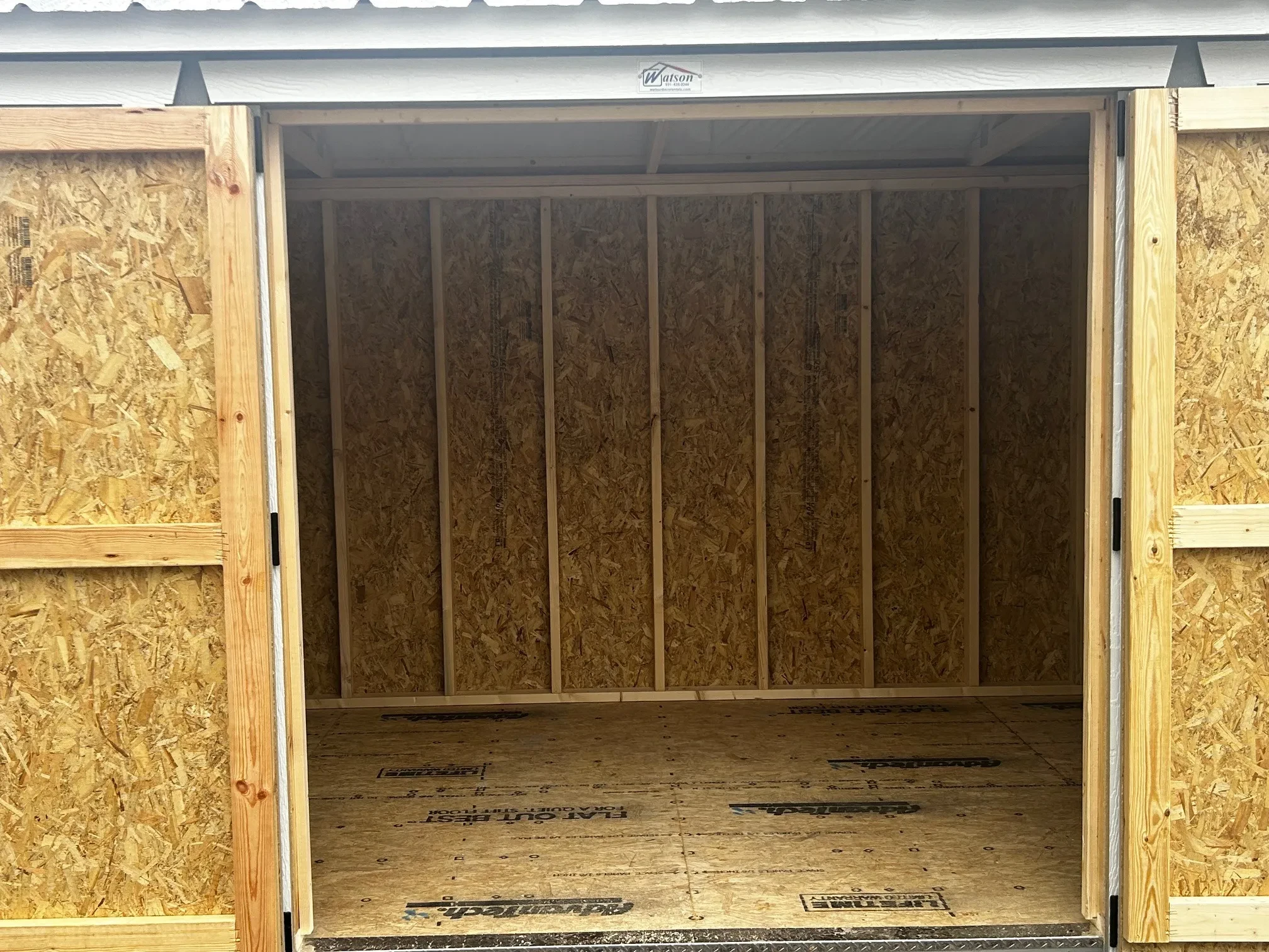 A wood garden shed with the double doors wide open