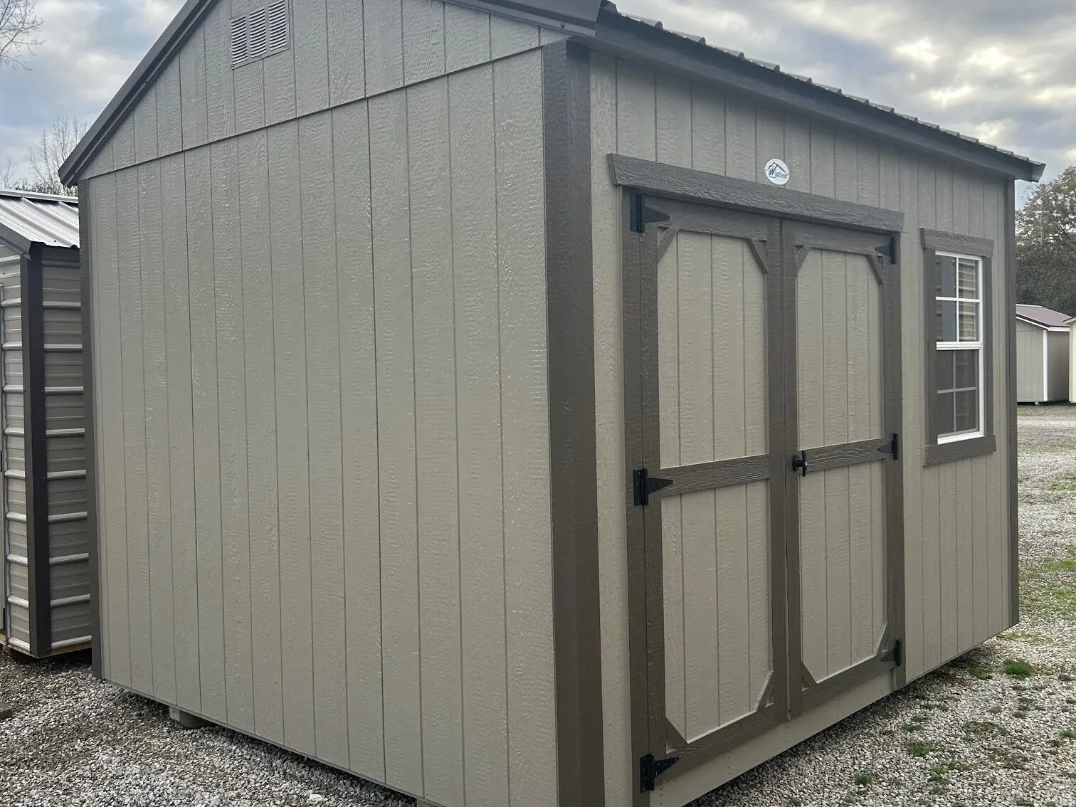 The front corner of a clay colored wood shed with a window