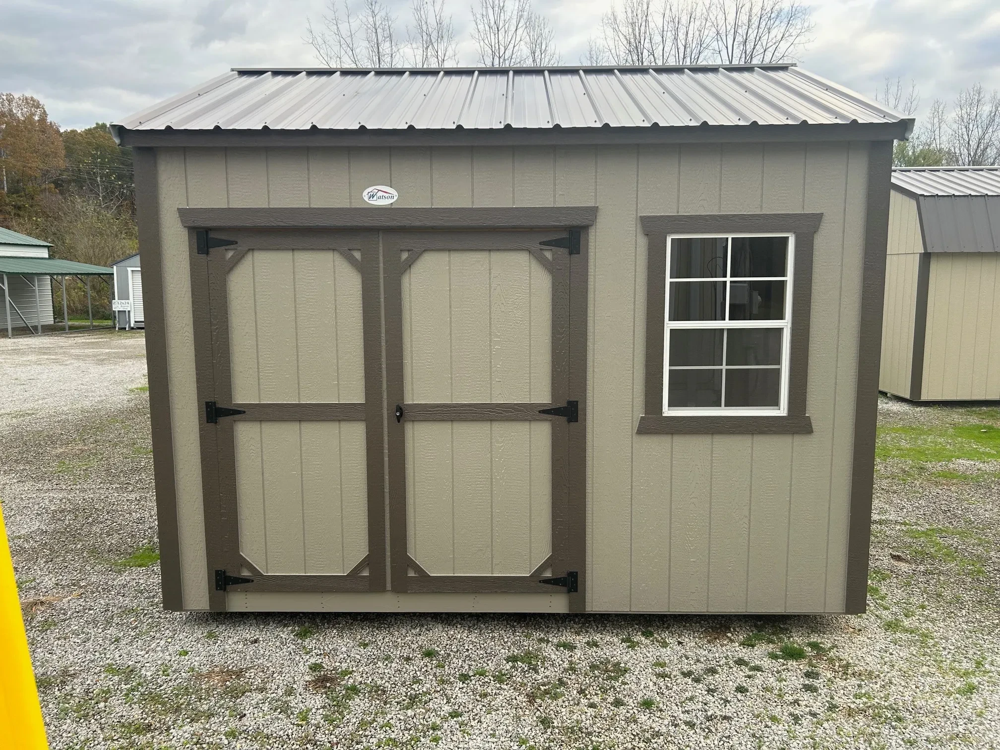 the front of a garden shed showing double doors and a window next to it