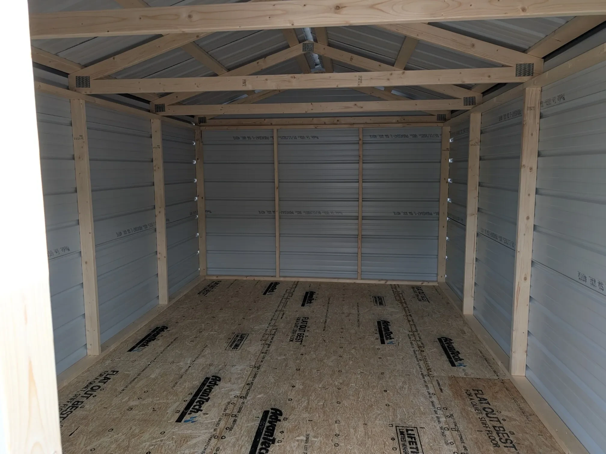 The inside of a gray metal shed showing the framing and floor