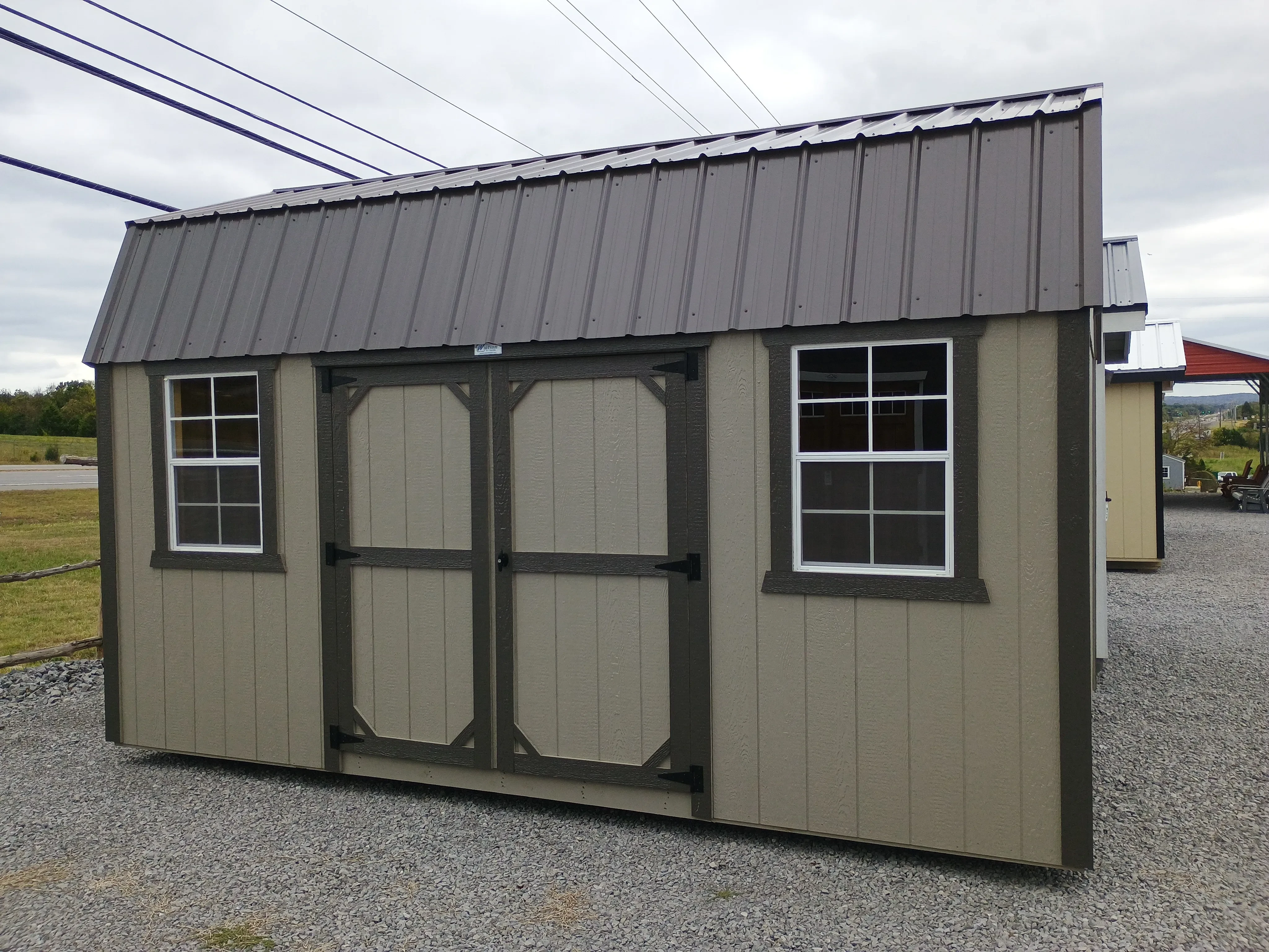 Outside of 10x16 painted side lofted barn shed, with double doors and two windows on the side, and metal roof.