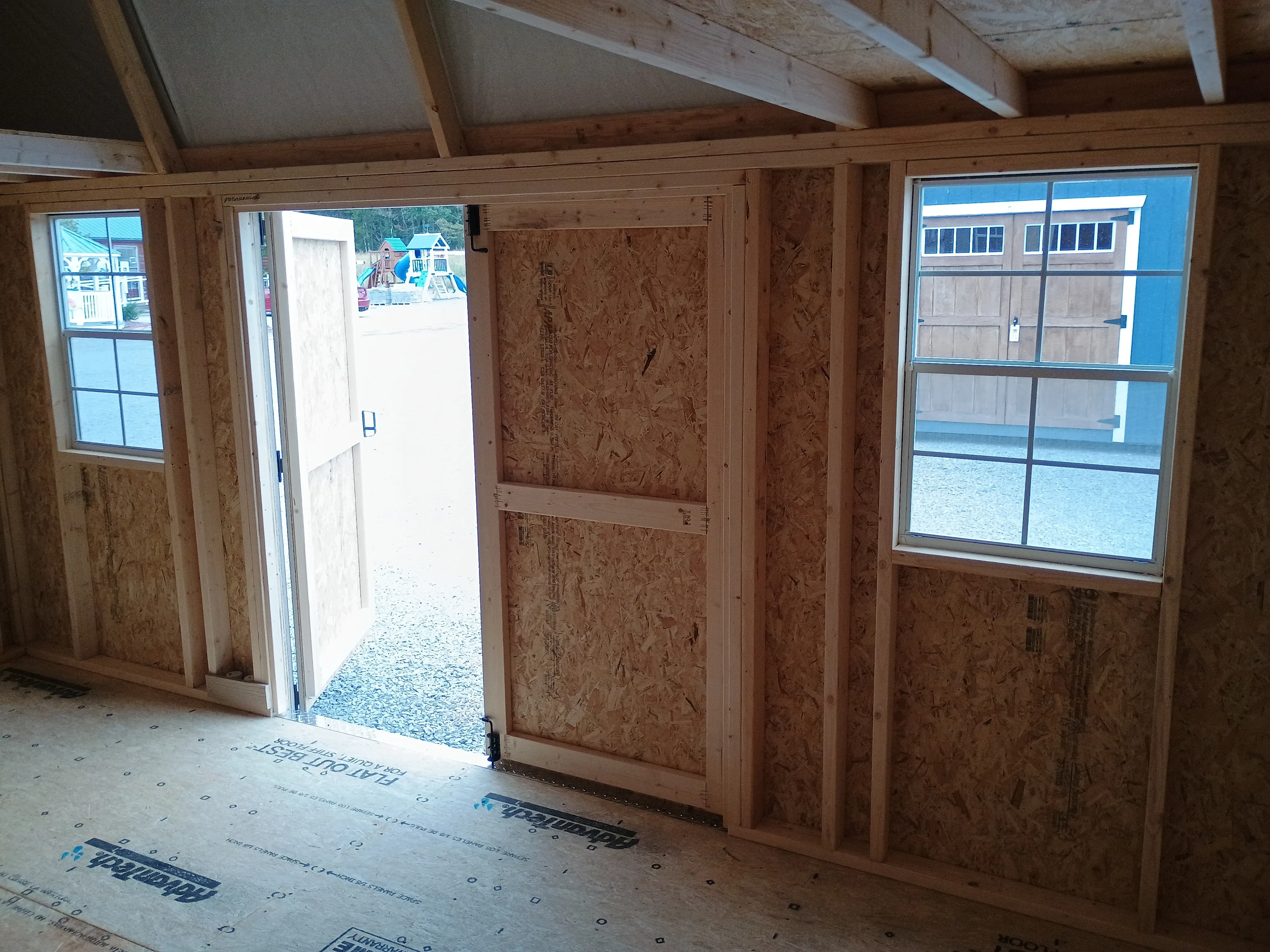 Inside of 10x16 painted side lofted barn shed, showing double doors and two windows from the interior.