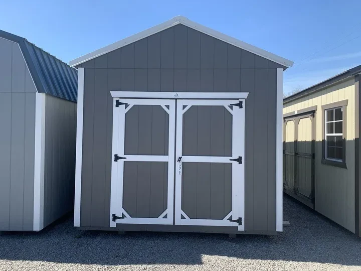 the front view of a gray wood shed with white trim