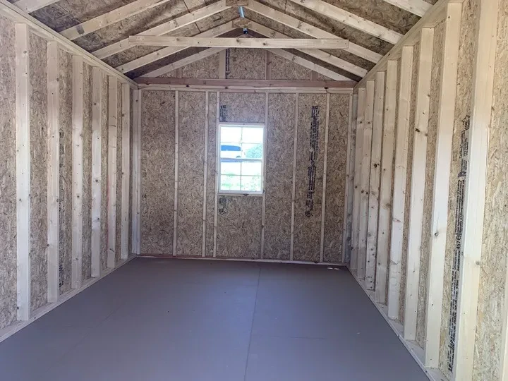 The inside of a wood shed with a 2x3 window in the middle of the back wall