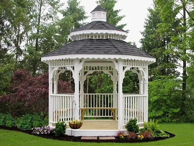 a beautifully landscaped white gazebo with shingle roof